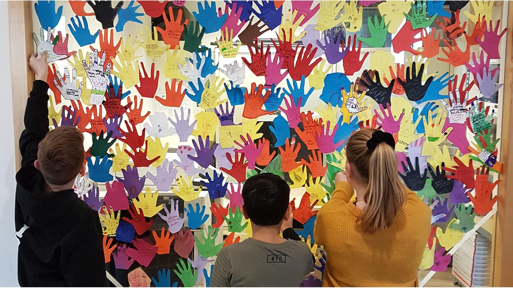 Leerlingen van PCBO De Diamant het Rooster in Apeldoorn richten een kleurrijke handjesmuur in als creatieve expressie. Leerlingen van PCBO De Diamant het Rooster in Apeldoorn richten een kleurrijke handjesmuur in als creatieve expressie.