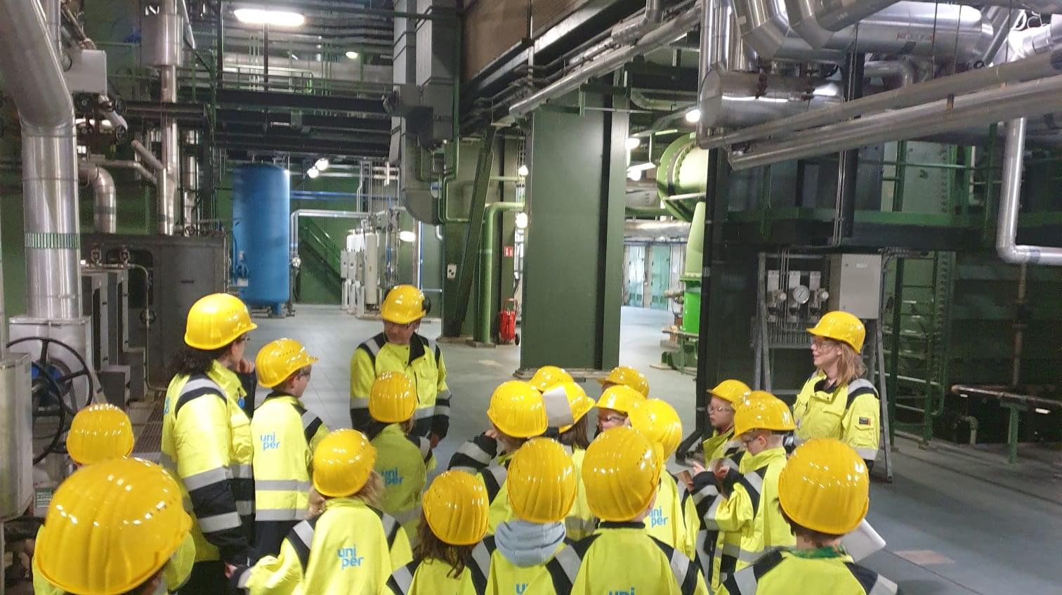 Leerlingen van Quadratum in Rotterdam nemen deel aan een excursie met veiligheidshelmen in een industriële omgeving.