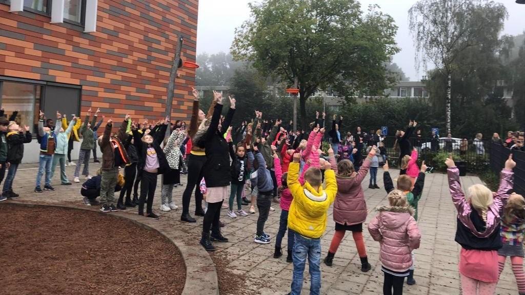 Leerlingen van RK/PC Jenaplanschool Kristalla in Emmen steken hun handen in de lucht op het schoolplein. Leerlingen van RK/PC Jenaplanschool Kristalla in Emmen steken hun handen in de lucht op het schoolplein.