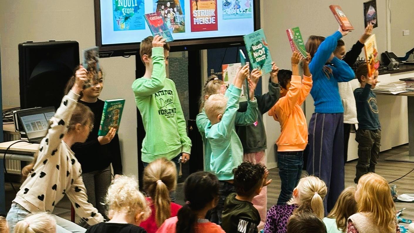 Leerlingen van Rooms Katholieke Basisschool De Schakel in Apeldoorn houden boeken omhoog tijdens een presentatie. Leerlingen van Rooms Katholieke Basisschool De Schakel in Apeldoorn houden boeken omhoog tijdens een presentatie.