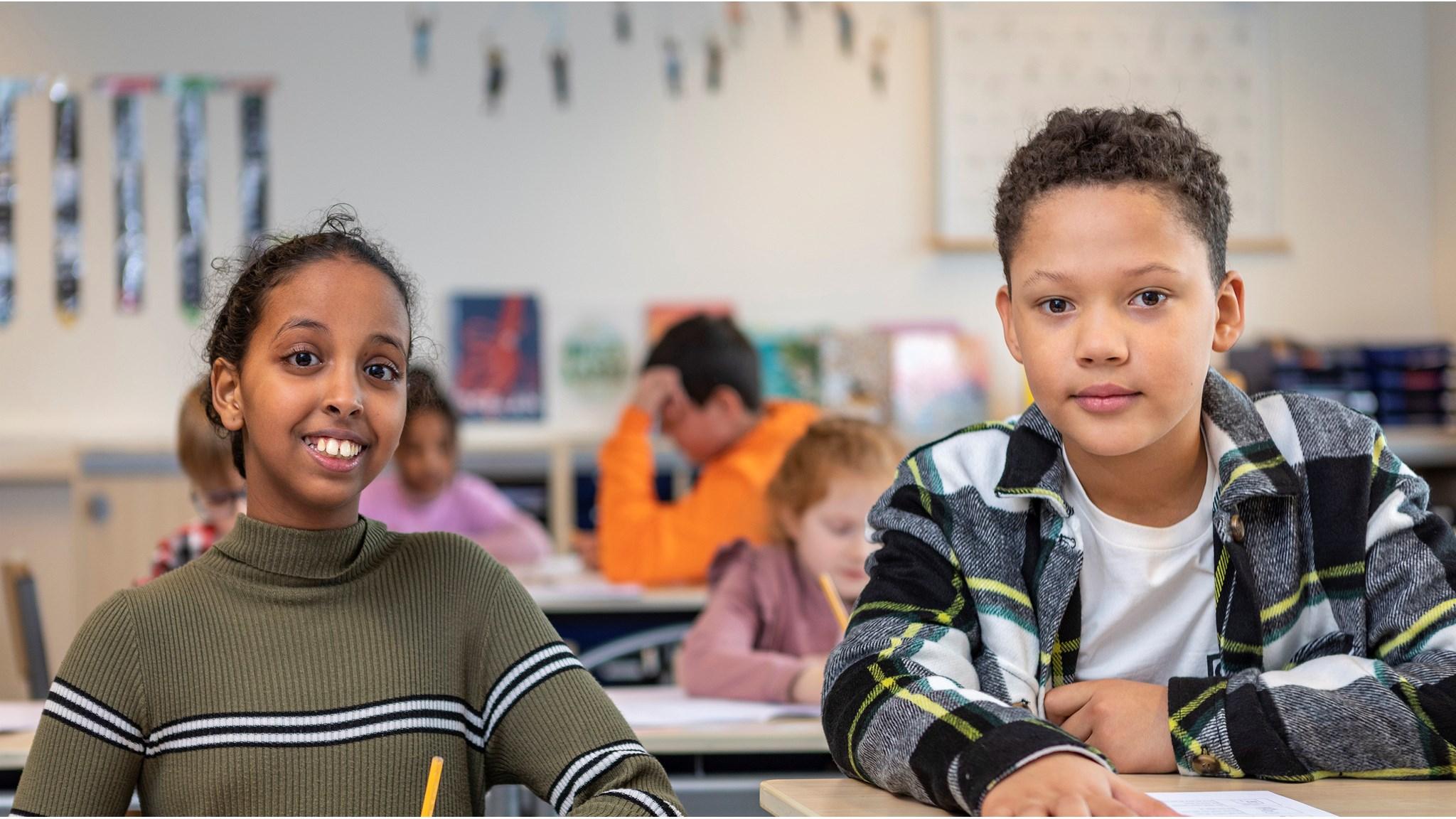 Leerlingen van School voor Speciaal Basisonderwijs De Kring in Rotterdam glimlachen terwijl ze in de klas zitten. Leerlingen van School voor Speciaal Basisonderwijs De Kring in Rotterdam glimlachen terwijl ze in de klas zitten.
