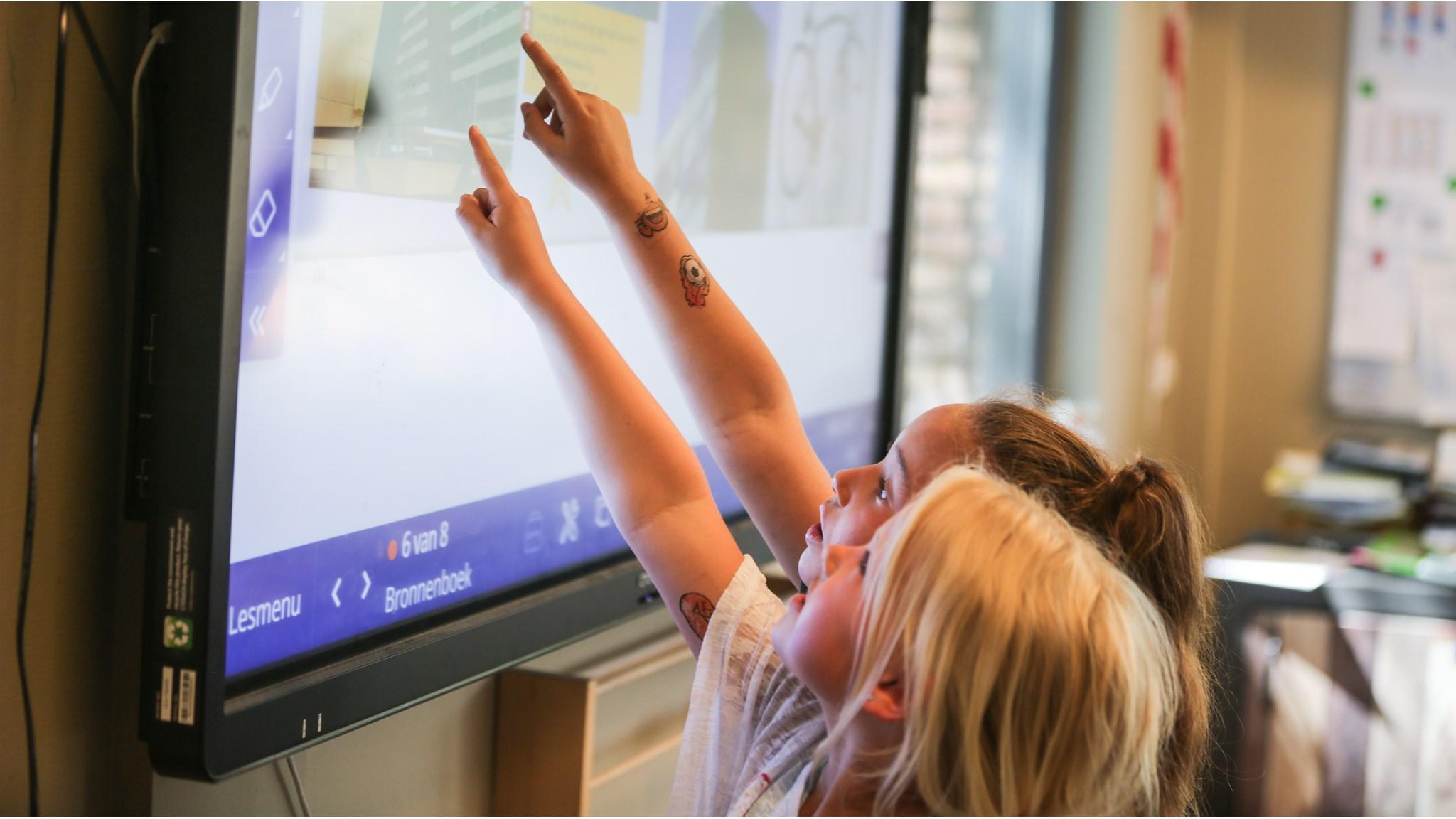Leerlingen van WSKO Mariaschool in Wateringen wijzen naar een interactief scherm tijdens de les. Leerlingen van WSKO Mariaschool in Wateringen wijzen naar een interactief scherm tijdens de les.
