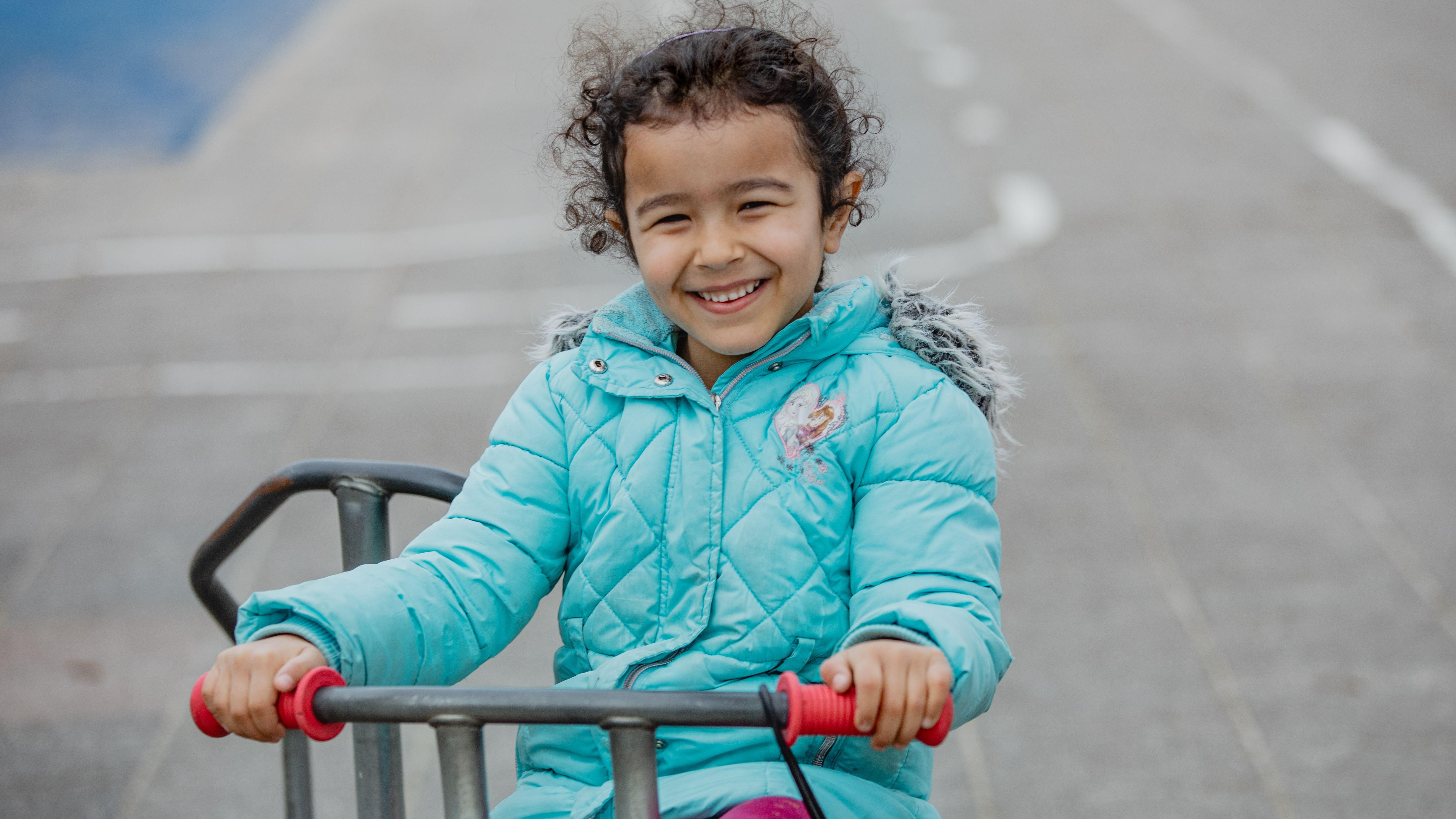 Meisje met een blauwe jas fietst vrolijk op het schoolplein van Openbare Basisschool Emmermeer in Emmen. Meisje met een blauwe jas fietst vrolijk op het schoolplein van Openbare Basisschool Emmermeer in Emmen.