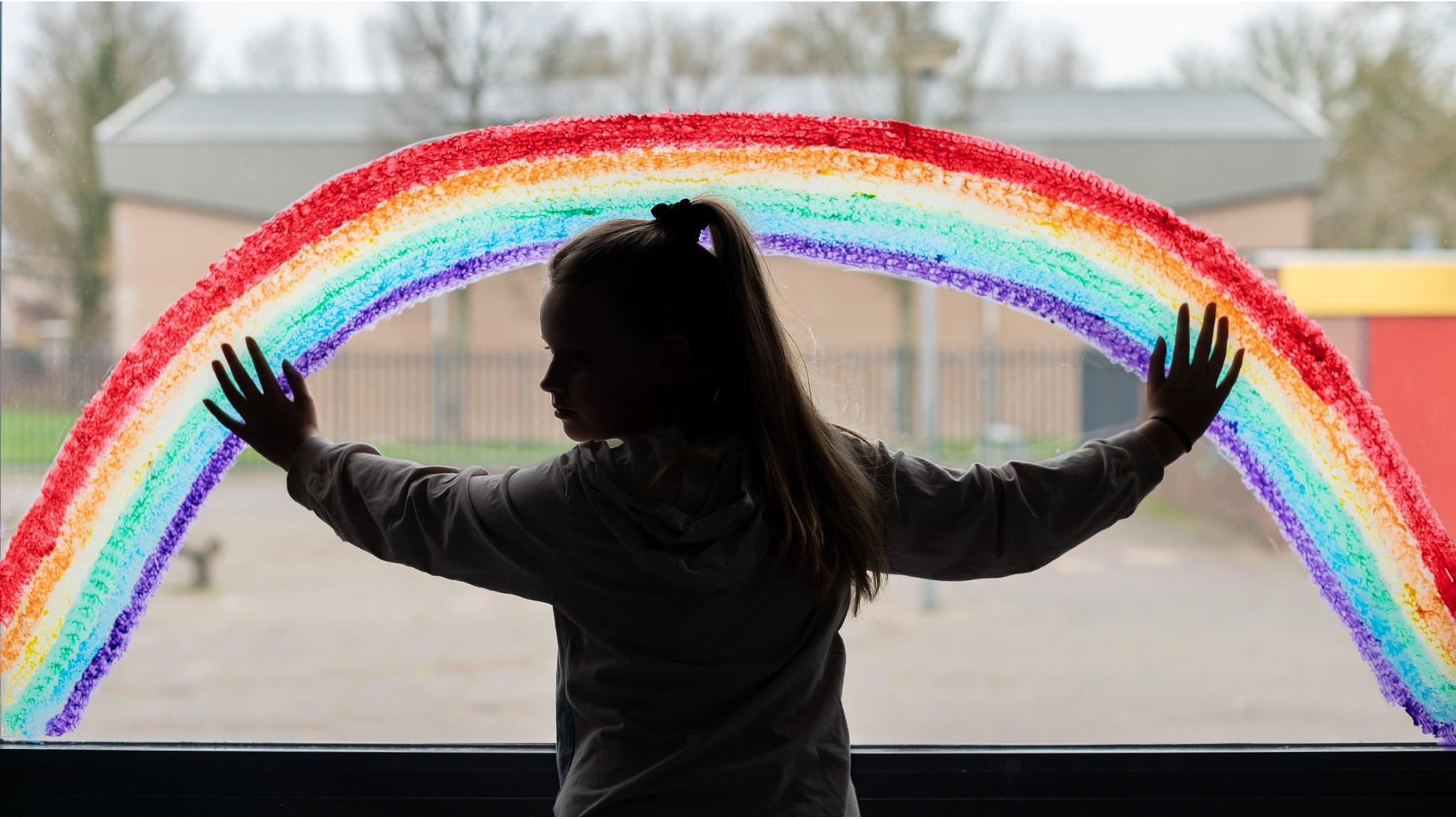 Meisje met een hand op een raam versierd met een kleurrijke regenboog op de school 'De Akker' in Opmeer. Meisje met een hand op een raam versierd met een kleurrijke regenboog op de school 'De Akker' in Opmeer.