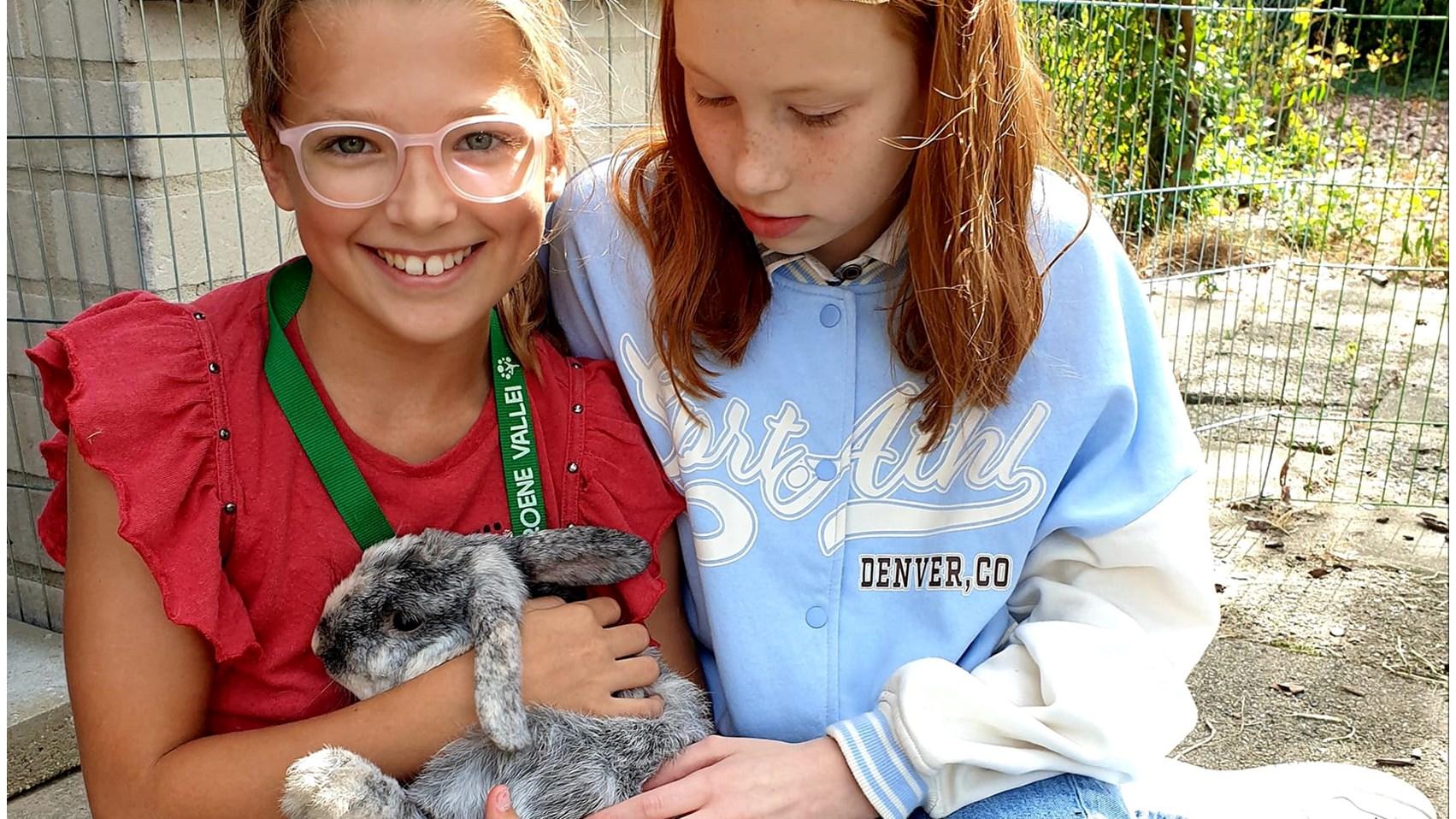 Meisjes van Basisschool Groene Vallei in Ede poseren met een konijn op het schoolplein.