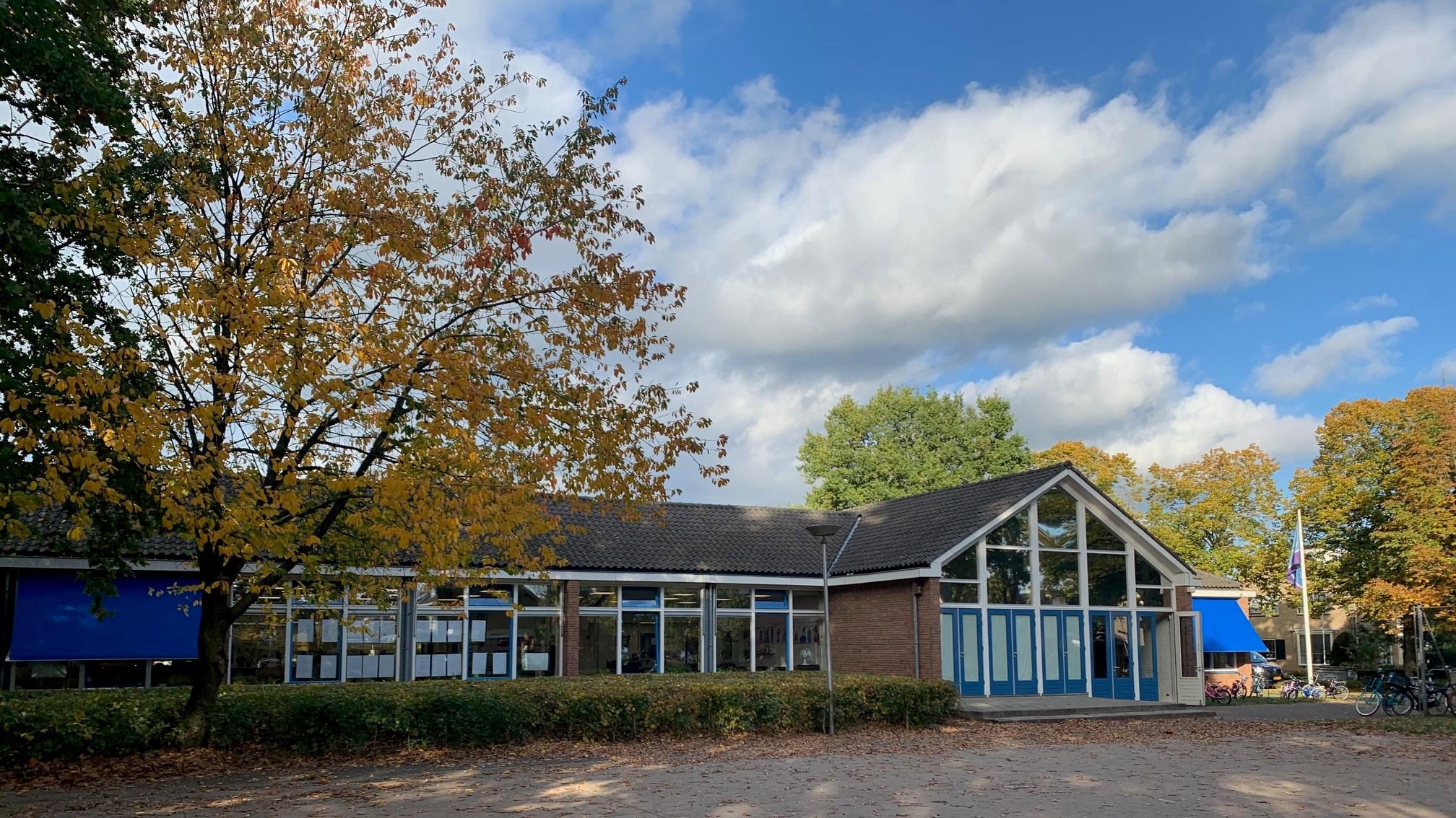 Obs De Campherbeek in Zwolle met een helder blauwe lucht en herfstachtige bomen rondom het schoolplein.