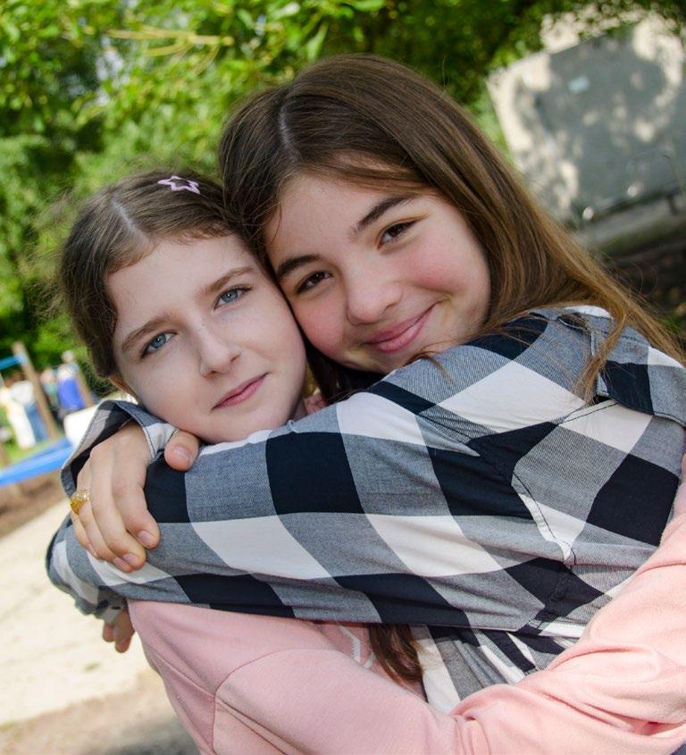 Openbare Basisschool Kamperfoelie in Huizen: Twee meisjes omhelzen elkaar vrolijk op het schoolplein. Openbare Basisschool Kamperfoelie in Huizen: Twee meisjes omhelzen elkaar vrolijk op het schoolplein.