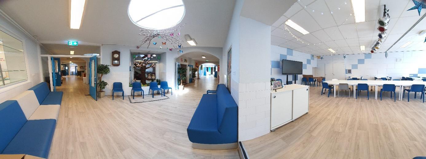 Panoramisch overzicht van een moderne gang in de Sint Jozef Basisschool in Volendam, met blauwe zitplaatsen en een uitnodigende leeromgeving. Panoramisch overzicht van een moderne gang in de Sint Jozef Basisschool in Volendam, met blauwe zitplaatsen en een uitnodigende leeromgeving.