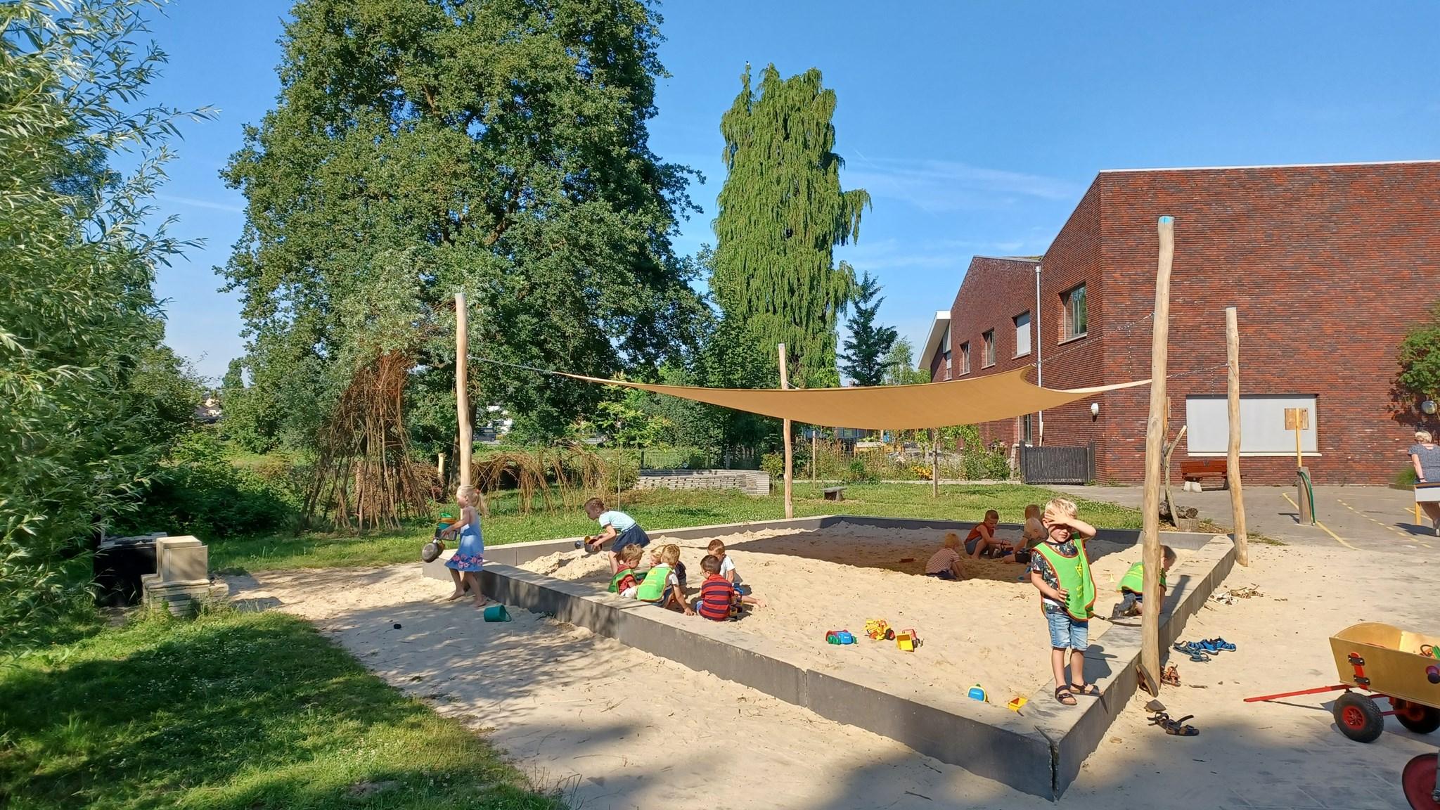 Schoolplein van Basisschool Heeckeren in Goor met spelende kinderen in een zandbak. Schoolplein van Basisschool Heeckeren in Goor met spelende kinderen in een zandbak.
