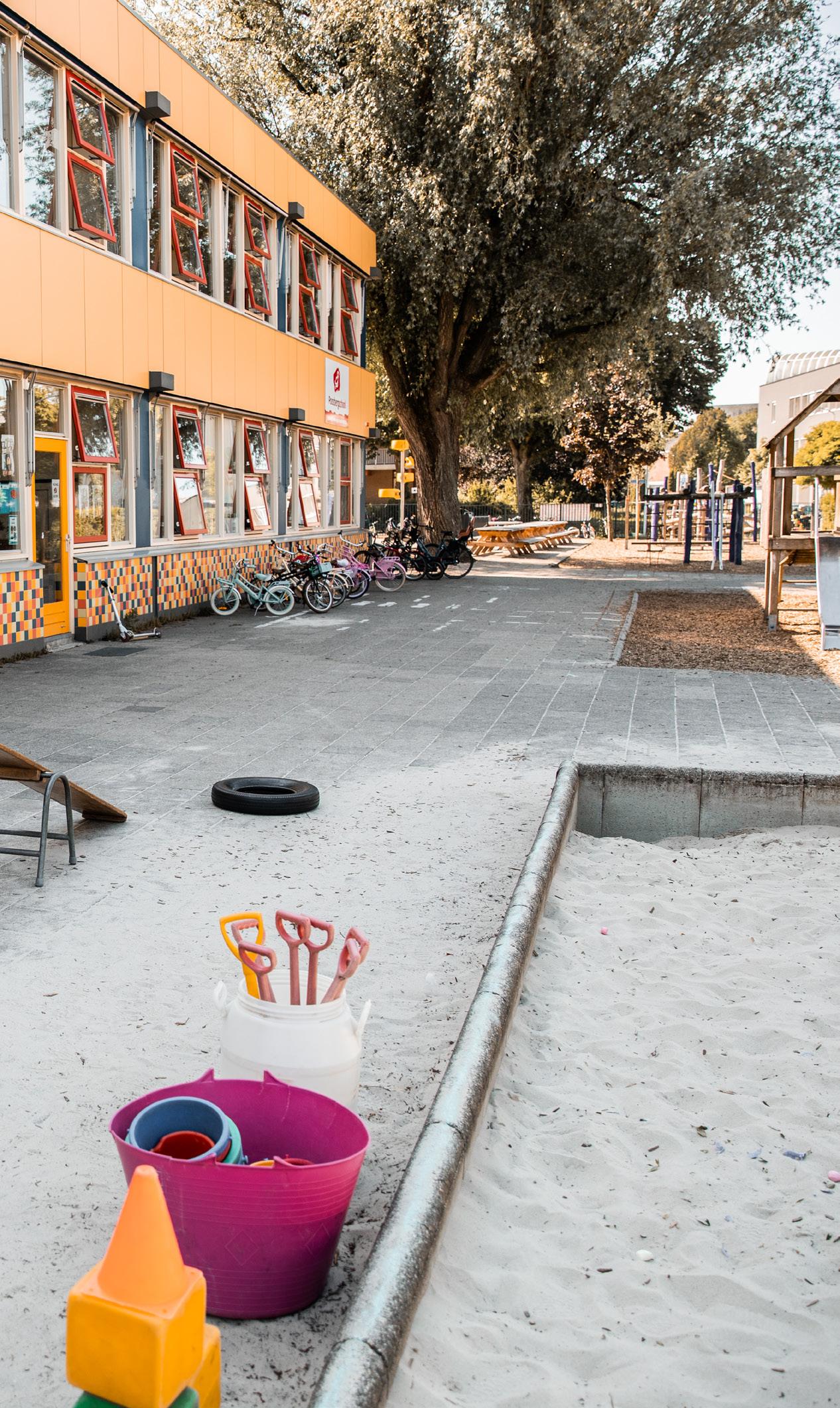Schoolplein van de Paasbergschool in Ede met speeltuin en speelmaterialen.