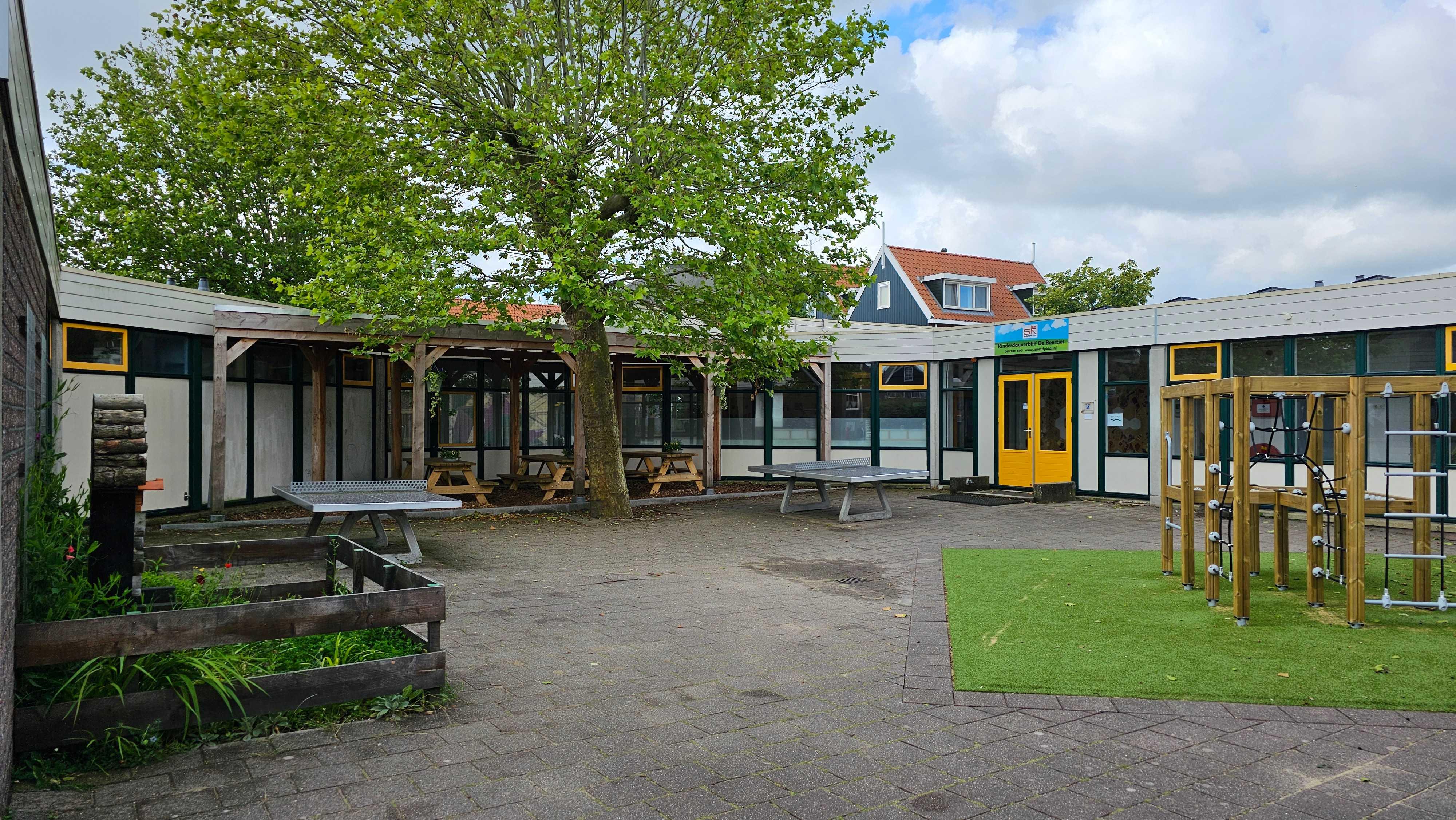 Schoolplein van De Rietlanden in Marken met speeltoestellen en groene bomen.