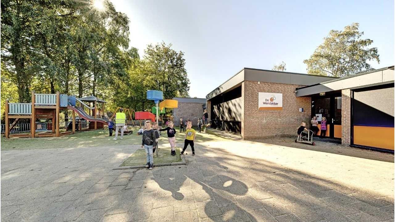 Schoolplein van De Wendakker in Oldenzaal met kinderen die spelen en een kleurrijke speeltuin op de achtergrond. Schoolplein van De Wendakker in Oldenzaal met kinderen die spelen en een kleurrijke speeltuin op de achtergrond.