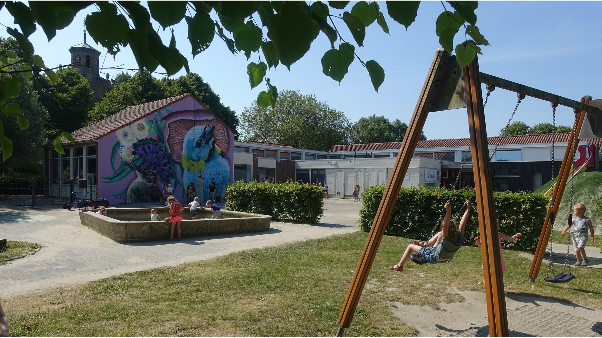 Schoolplein van Kindcentrum De Poeljeugd in 's-Heer Hendrikskinderen met kleurrijke muurschilderingen en kinderen die spelen. Schoolplein van Kindcentrum De Poeljeugd in 's-Heer Hendrikskinderen met kleurrijke muurschilderingen en kinderen die spelen.