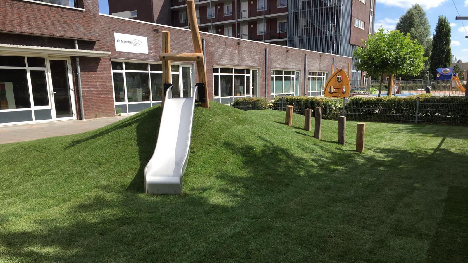 Schoolplein van Openbare Basisschool De Tuimelaar in Veghel met een glijbaan en natuurlijks speelemateriaal. Schoolplein van Openbare Basisschool De Tuimelaar in Veghel met een glijbaan en natuurlijks speelemateriaal.