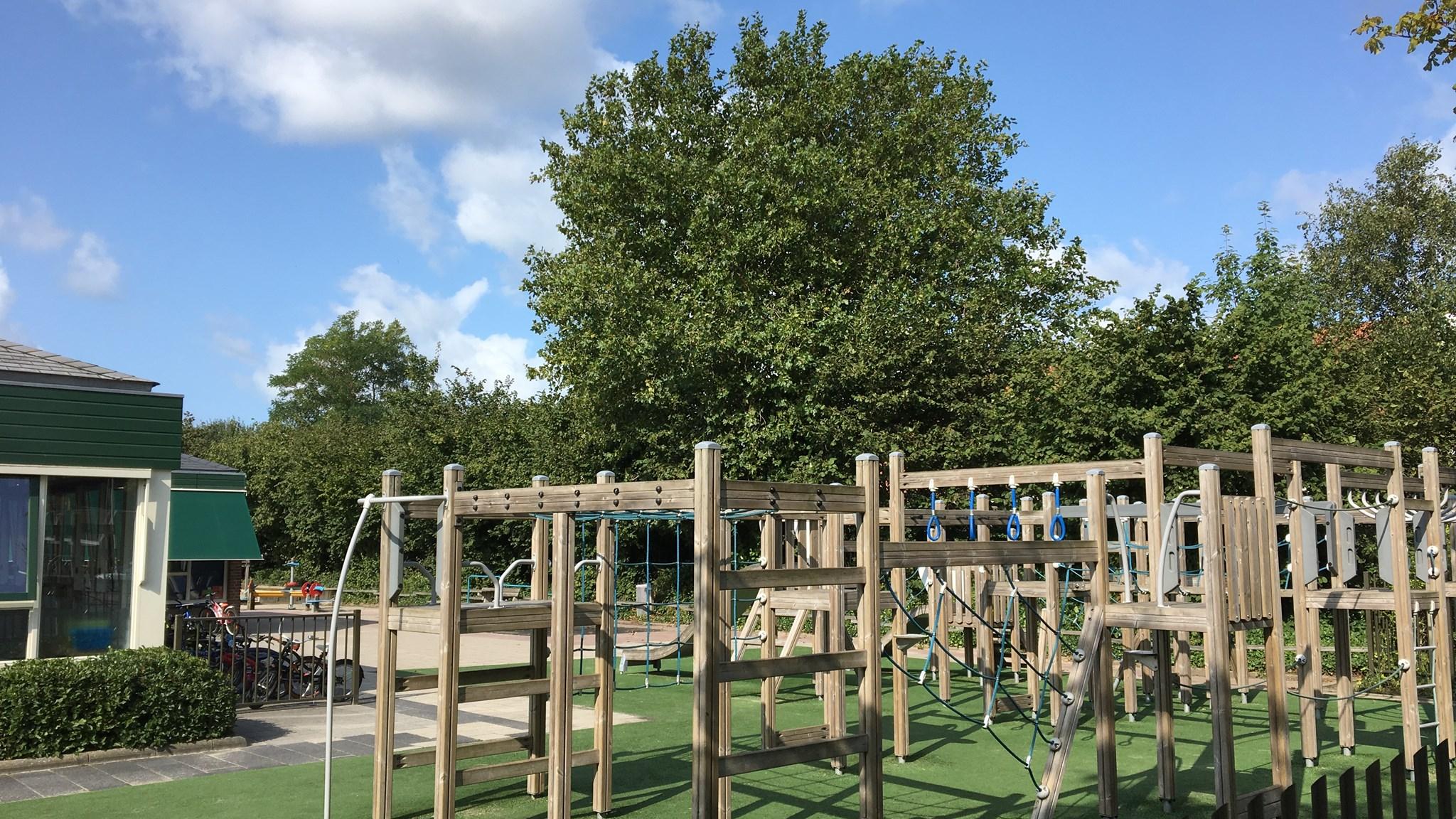 Schoolplein van Openbare Basisschool De Westhoek in Ouddorp met speeltoestellen en groen.