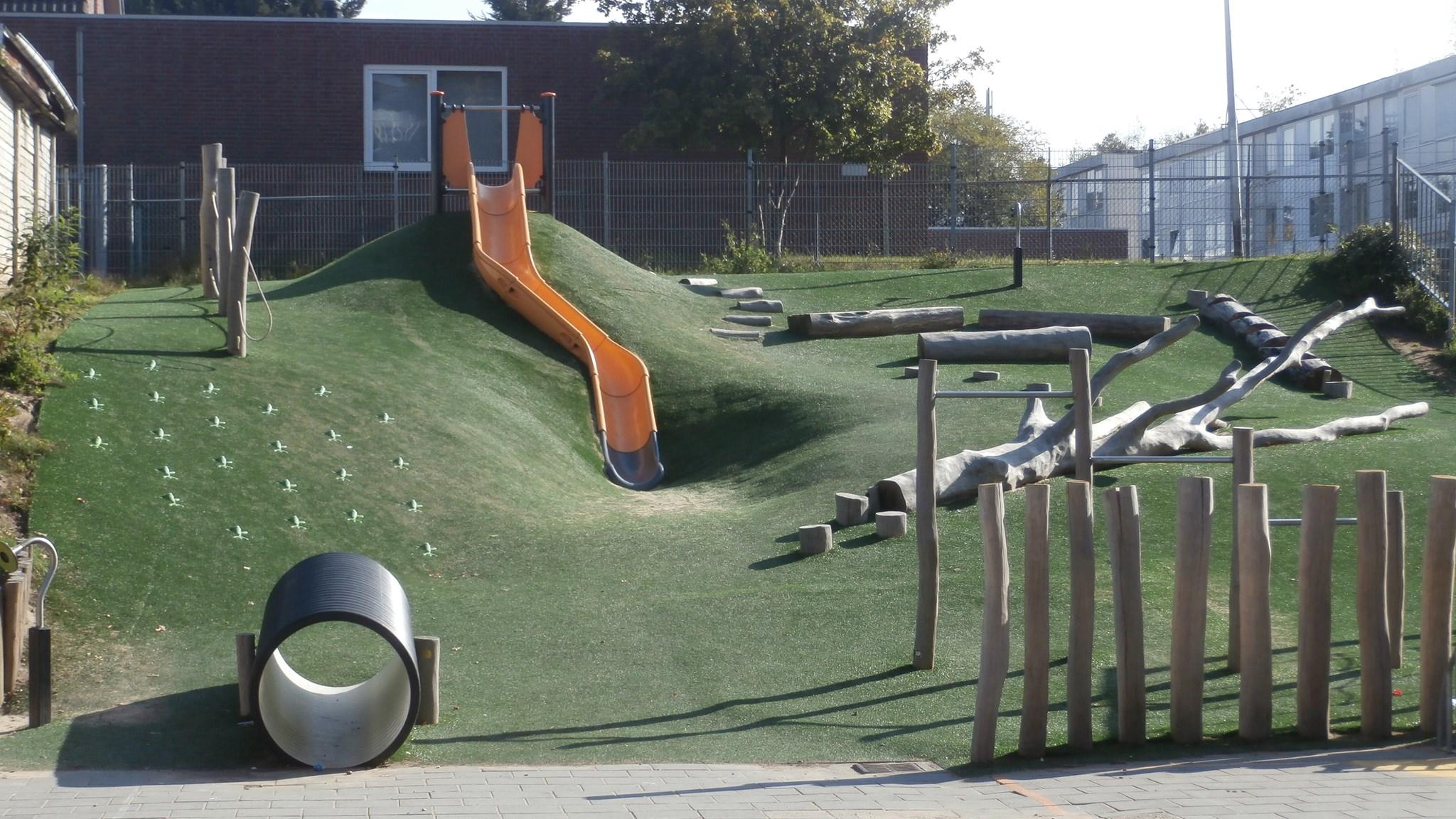 Speelplaats van de Rooms Katholieke Basisschool De Schakel in Heerlen met een glijbaan en natuurlijke speelstructuren. Speelplaats van de Rooms Katholieke Basisschool De Schakel in Heerlen met een glijbaan en natuurlijke speelstructuren.