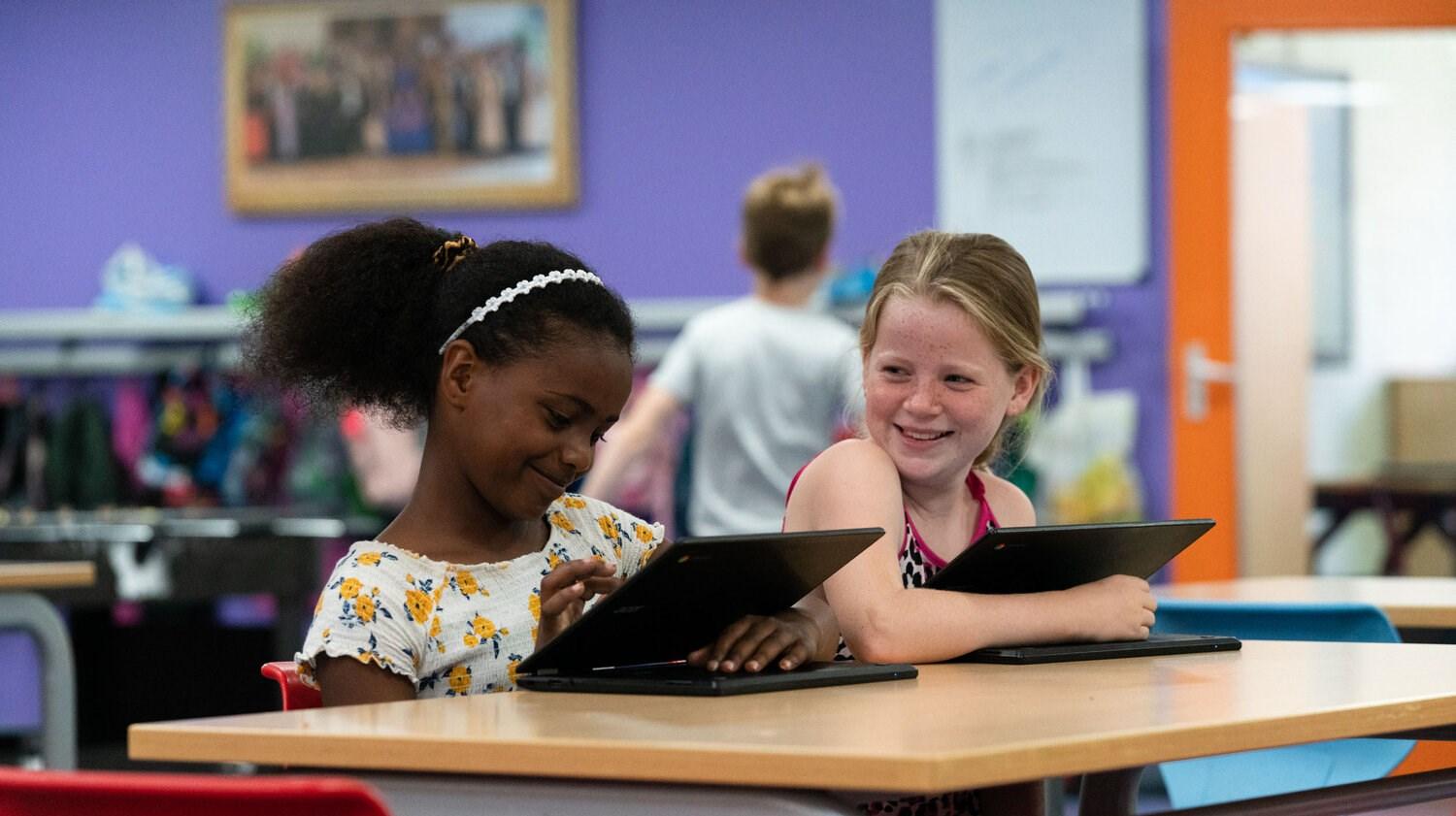 Twee blije kinderen aan het werken met tablets in de klas van Openbare Basisschool De Bijenkorf in Houten. Twee blije kinderen aan het werken met tablets in de klas van Openbare Basisschool De Bijenkorf in Houten.
