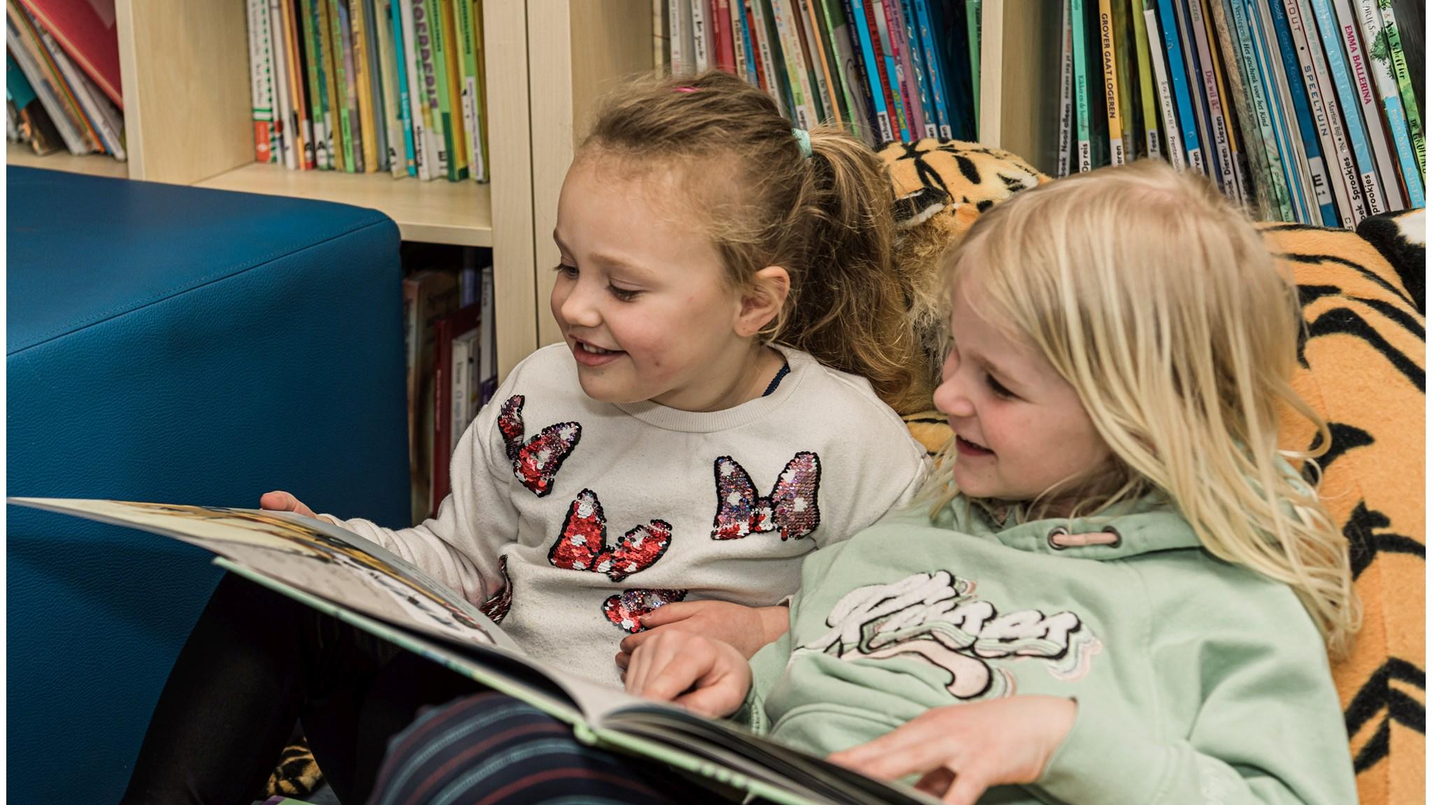 Twee blije kinderen lezen samen in de bibliotheek van Oecumenische Basisschool De Binnendijk in Monnickendam. Twee blije kinderen lezen samen in de bibliotheek van Oecumenische Basisschool De Binnendijk in Monnickendam.