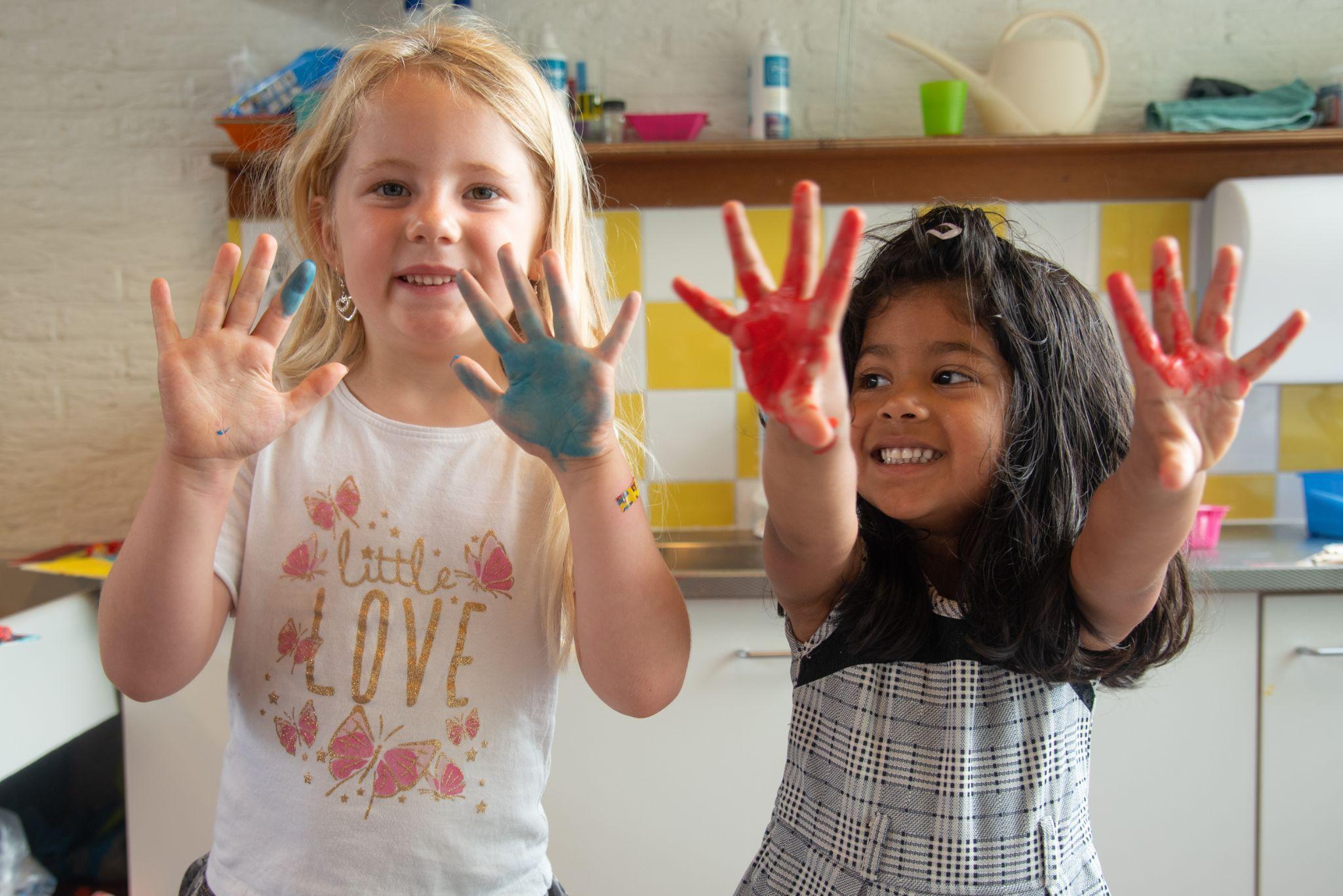 Twee blije kinderen met geverfde handen in de keuken van Basisschool Wisperweide in Weesp. Twee blije kinderen met geverfde handen in de keuken van Basisschool Wisperweide in Weesp.