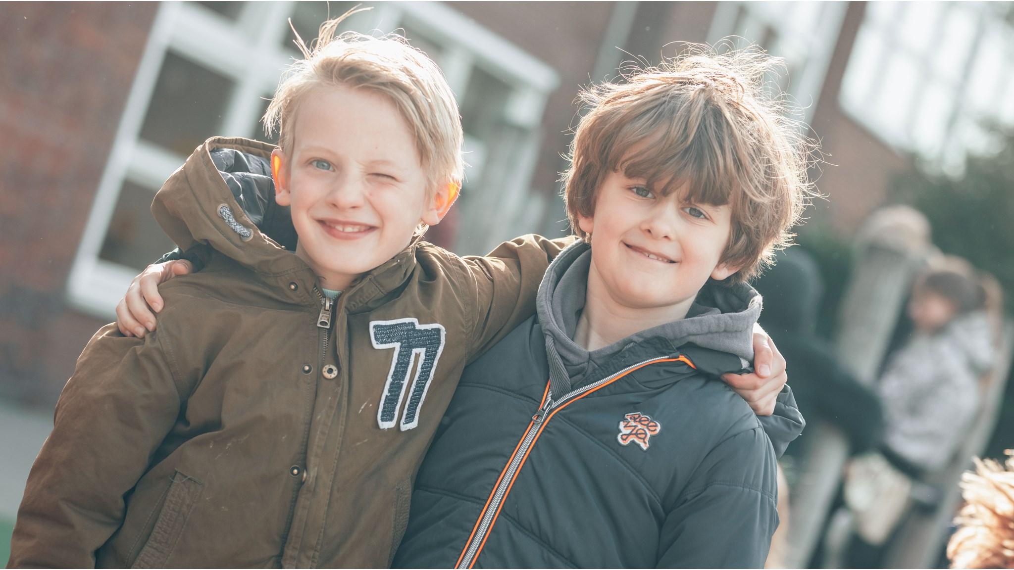 Twee blije kinderen op het schoolplein van Dr. De Visserschool in Breda.