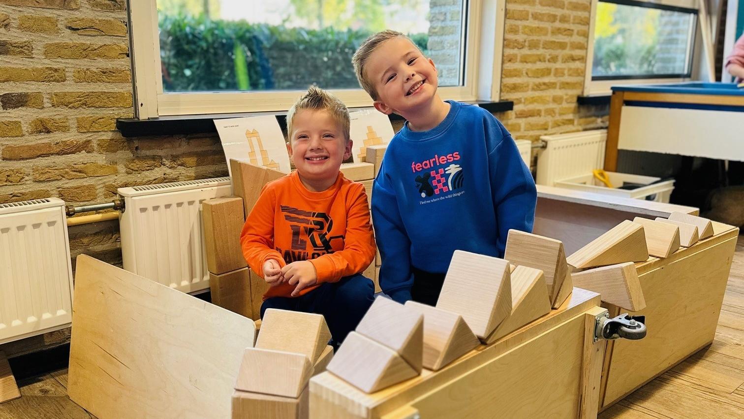 Twee blije kinderen spelen met houten blokken in Basisschool De Hoge Waai in Raamsdonk. Twee blije kinderen spelen met houten blokken in Basisschool De Hoge Waai in Raamsdonk.