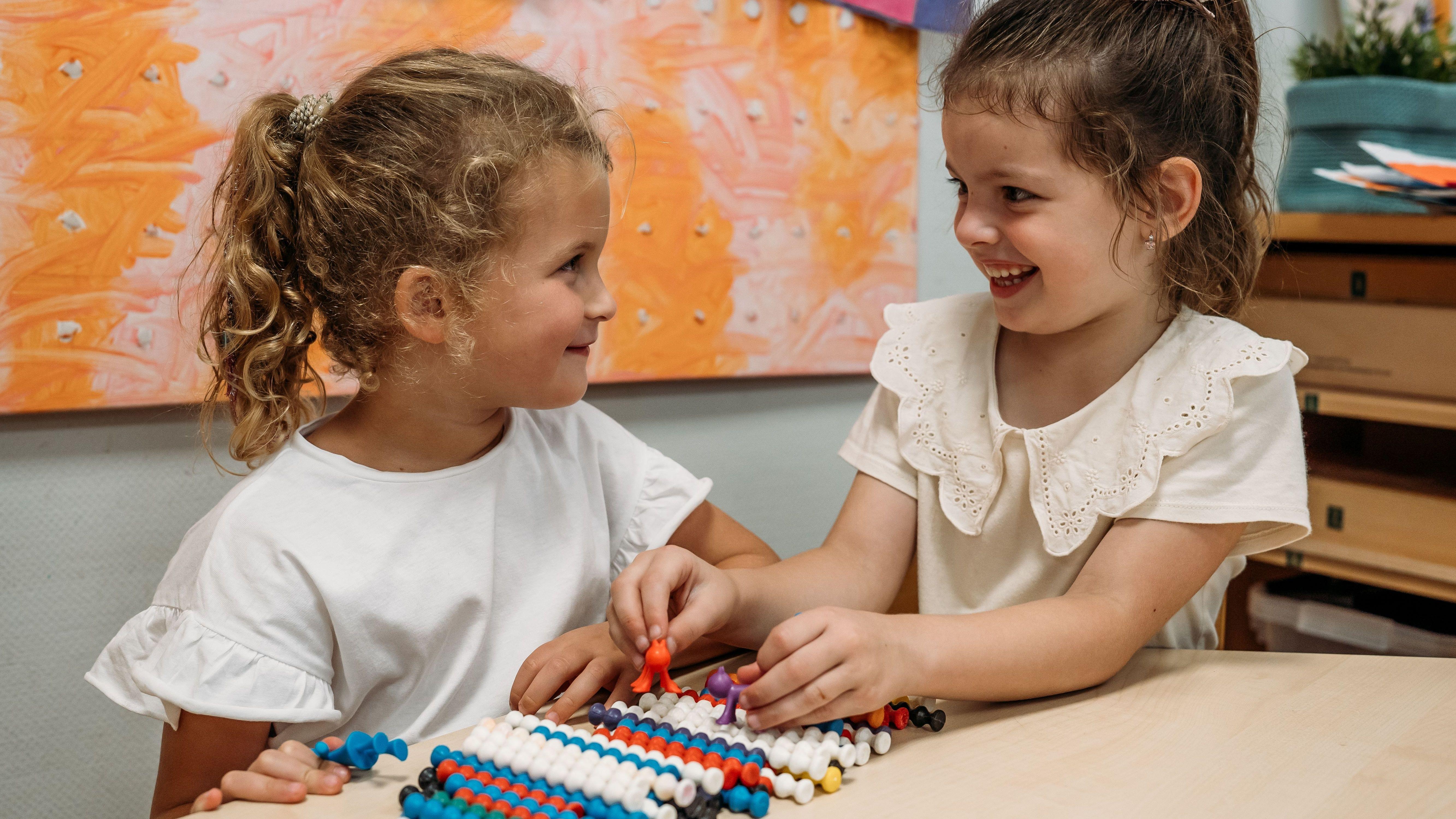 Twee blije kinderen spelen samen met kleurrijk speelgoed in de klas van KC Het IJzeren Kind in Rosmalen.