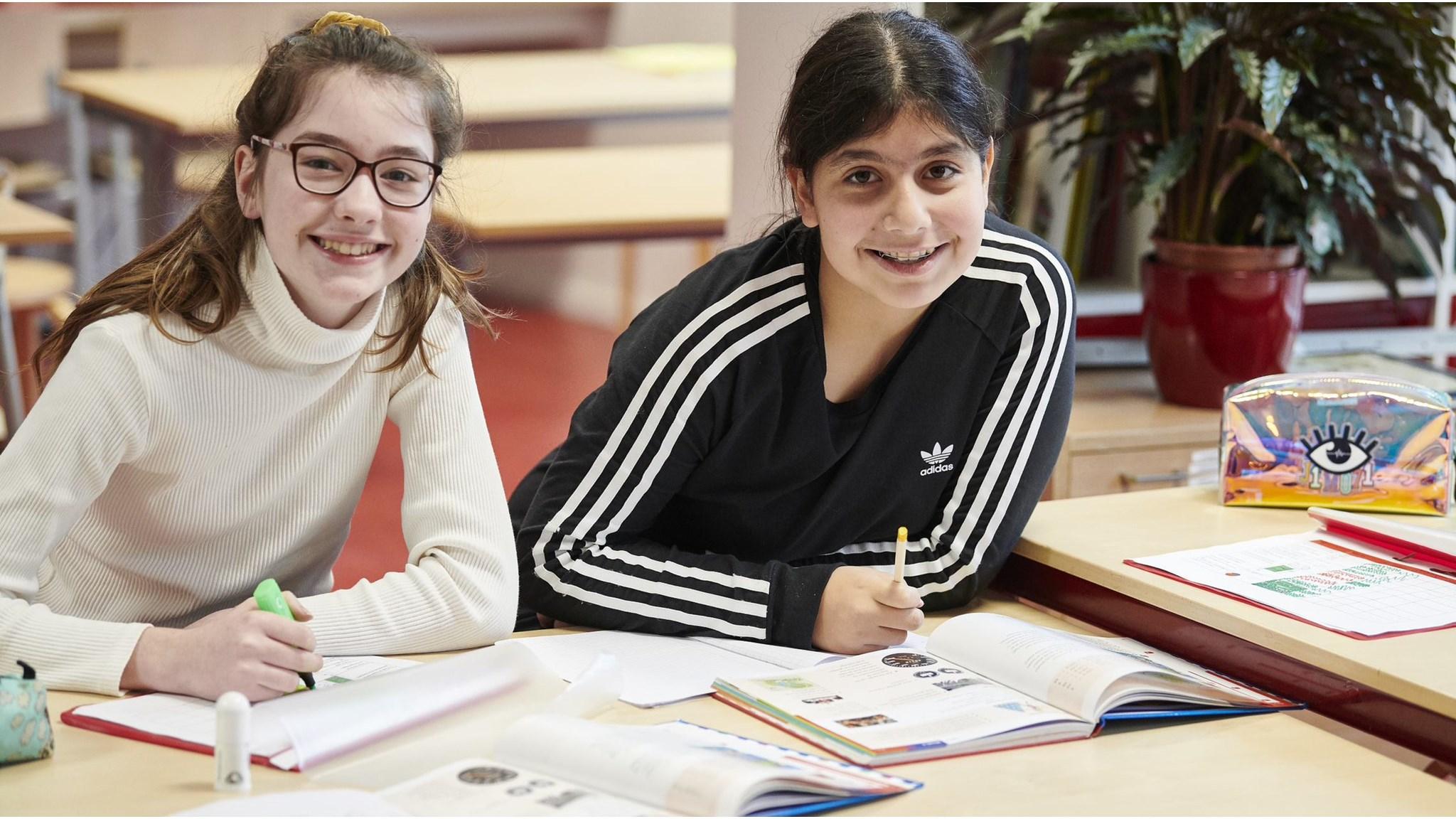 Twee blije leerlingen werken samen in de klas van Basisschool Hubertus in Tilburg. Twee blije leerlingen werken samen in de klas van Basisschool Hubertus in Tilburg.