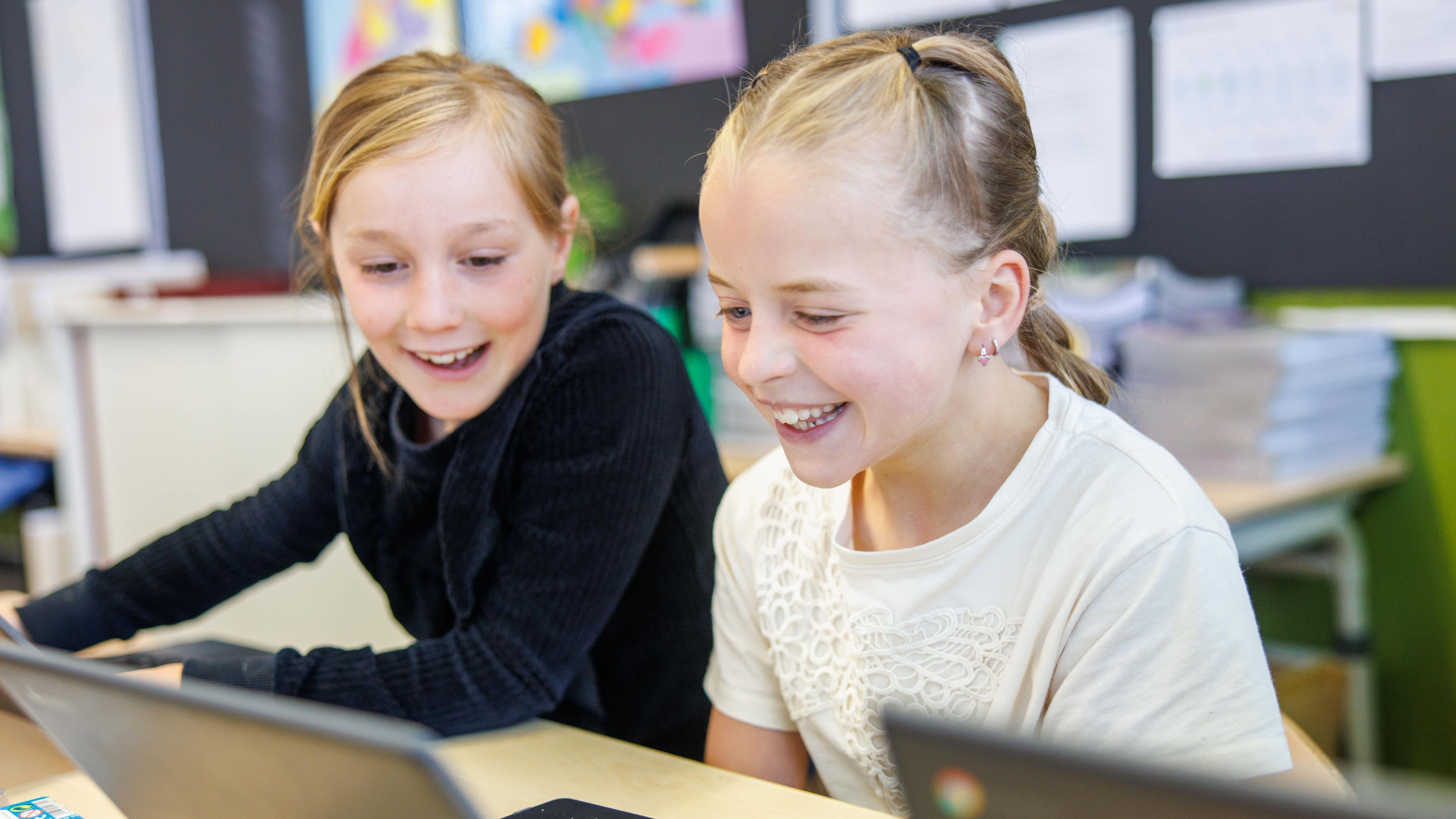Twee blije meisjes hebben plezier tijdens het werken op laptops op de Christelijke Basisschool De Wingerd in Ridderkerk. Twee blije meisjes hebben plezier tijdens het werken op laptops op de Christelijke Basisschool De Wingerd in Ridderkerk.