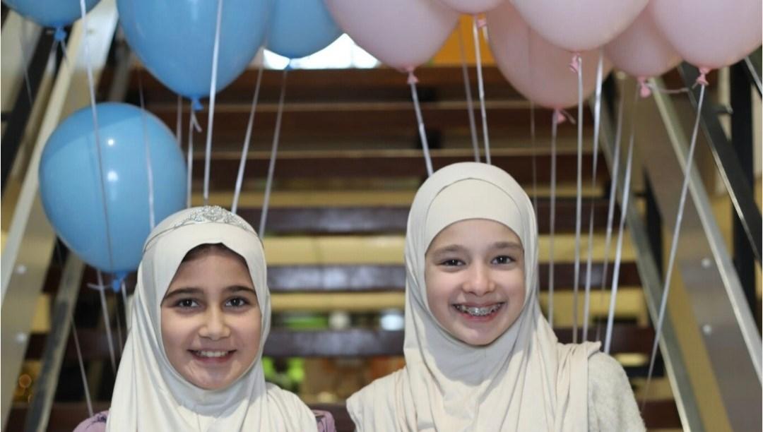 Twee blije meisjes met ballonnen op de trap van Al Ummah in Enschede.