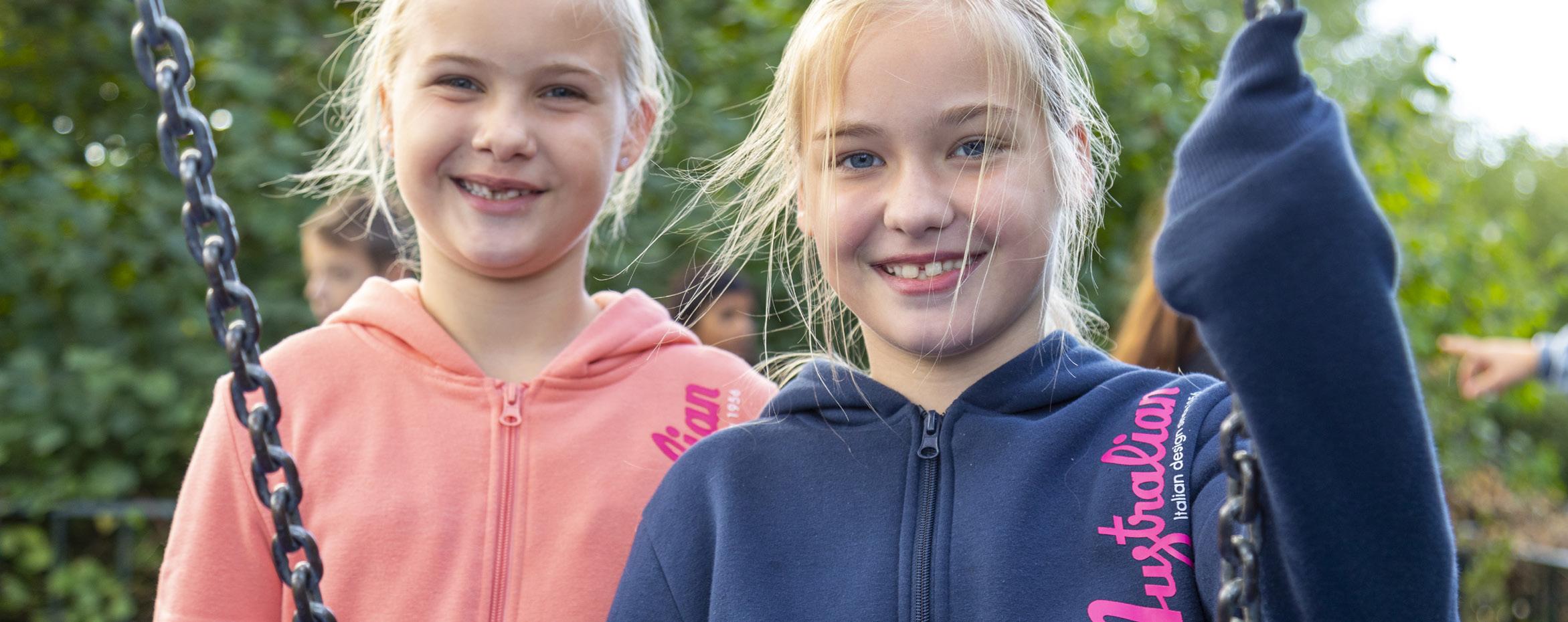 Twee blije meisjes spelen op het schoolplein van De Brug in IJsselstein.