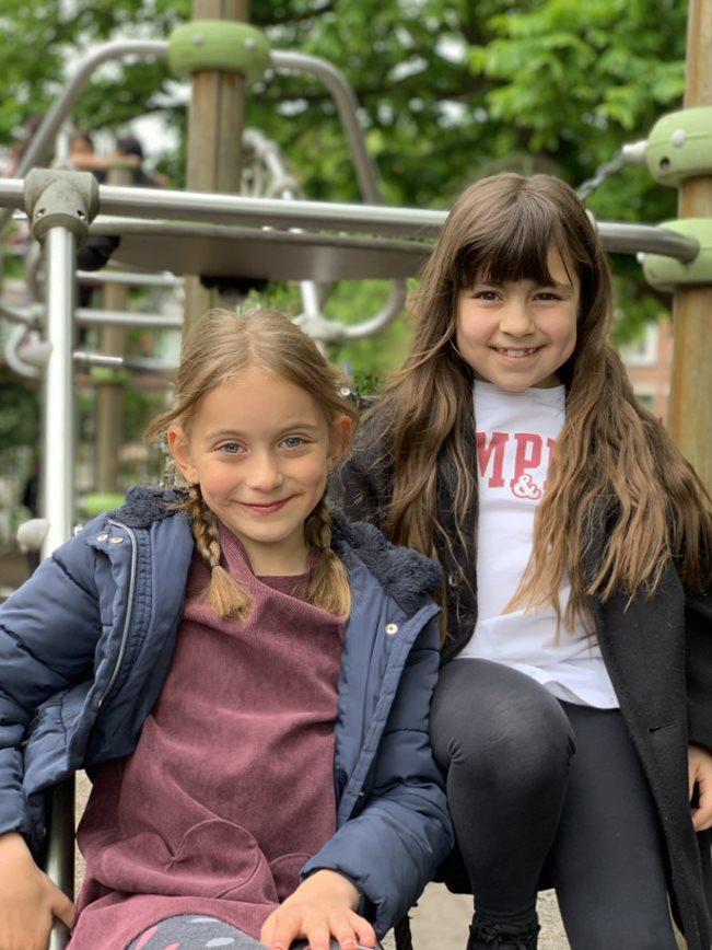 Twee blije meisjes zitten op het schoolplein van de Prinses Marijkeschool in Den Haag. Twee blije meisjes zitten op het schoolplein van de Prinses Marijkeschool in Den Haag.