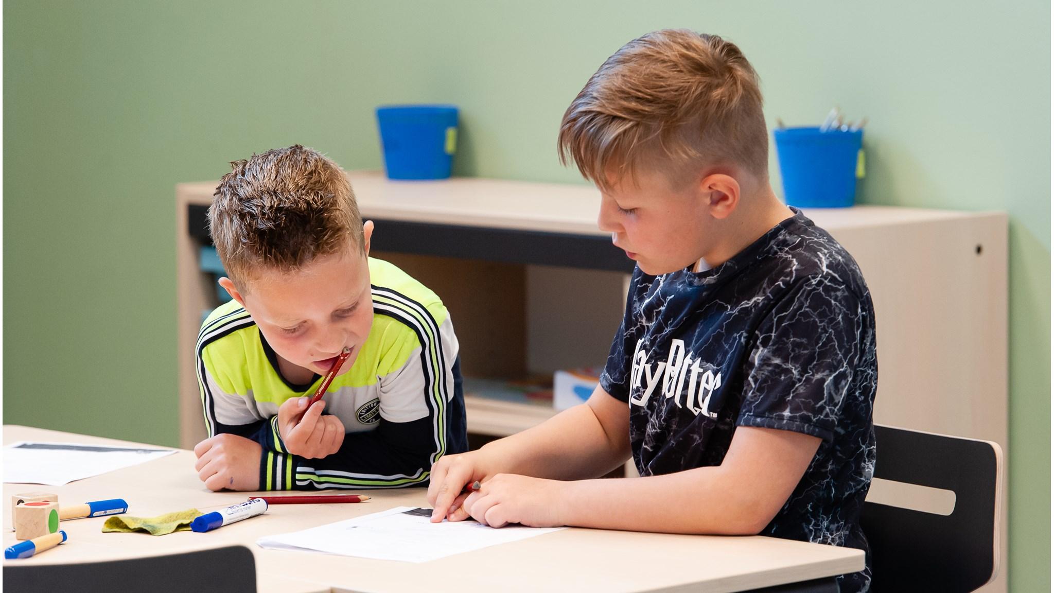 Twee jongens werken samen aan hun opdrachten in het klaslokaal van Integraal Kind Centrum Het Klokhuis in Duiven. Twee jongens werken samen aan hun opdrachten in het klaslokaal van Integraal Kind Centrum Het Klokhuis in Duiven.