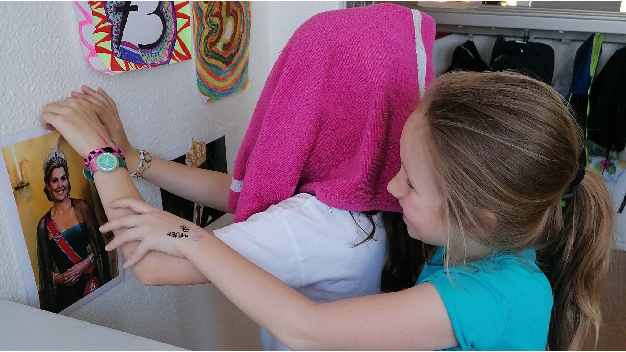 Twee kinderen aan de Lidwinaschool in Amsterdam hangen een foto op terwijl ze met elkaar spelen. Twee kinderen aan de Lidwinaschool in Amsterdam hangen een foto op terwijl ze met elkaar spelen.