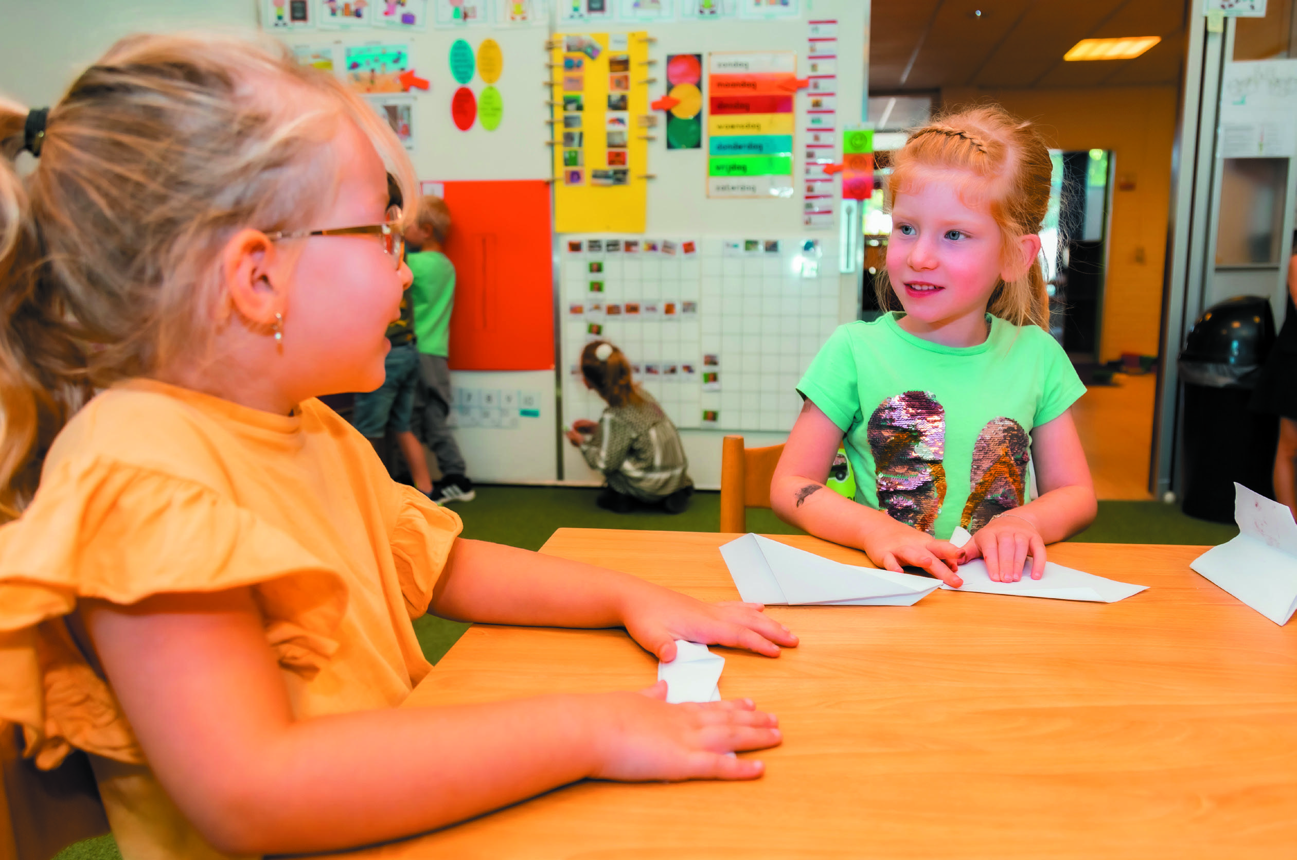 Twee kinderen aan een tafel in De Trompetvogel, Nieuwegein, terwijl ze papier vouwen. Twee kinderen aan een tafel in De Trompetvogel, Nieuwegein, terwijl ze papier vouwen.