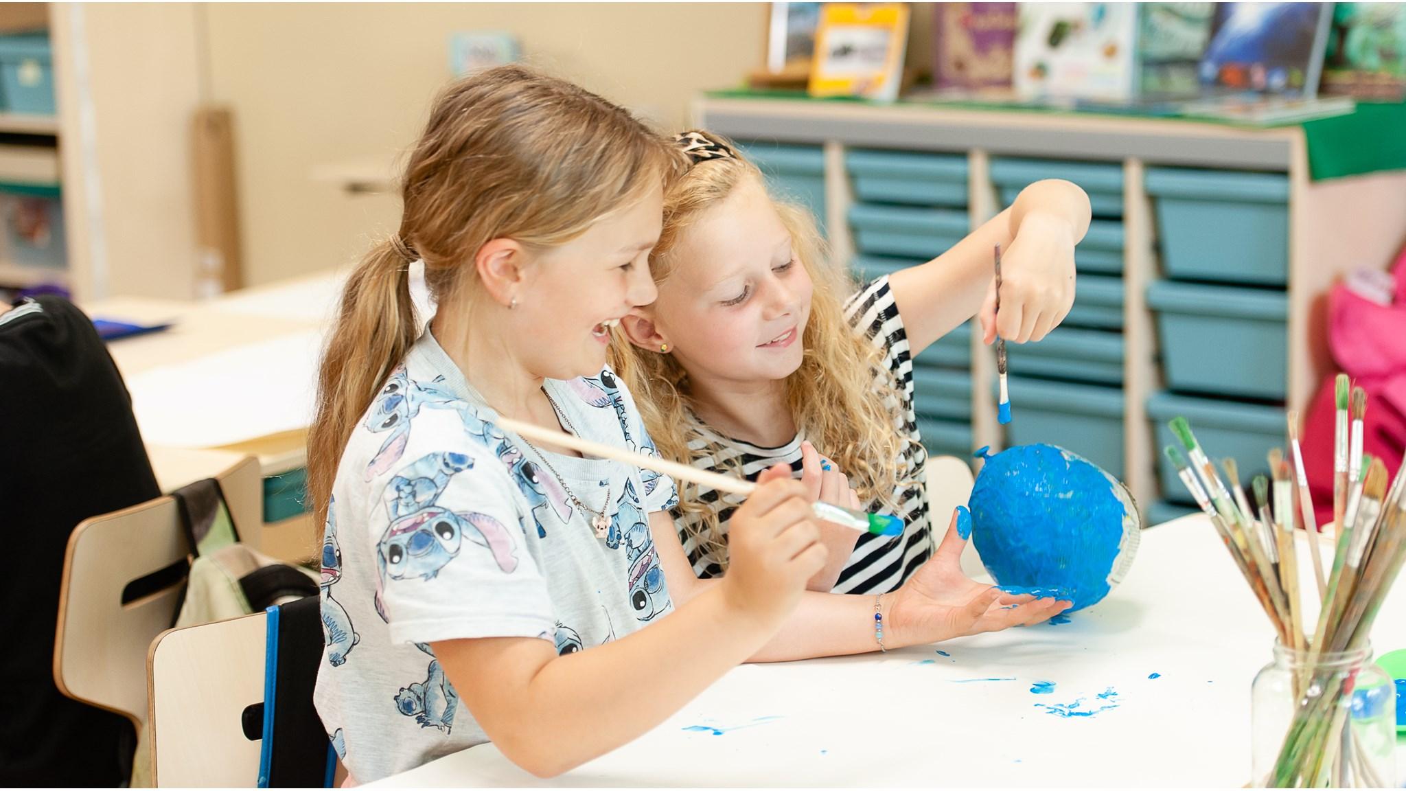 Twee kinderen aan 'Jenaplan IKC Donatushof' in Bemmel zijn vrolijk bezig met het schilderen van een globe. Twee kinderen aan 'Jenaplan IKC Donatushof' in Bemmel zijn vrolijk bezig met het schilderen van een globe.