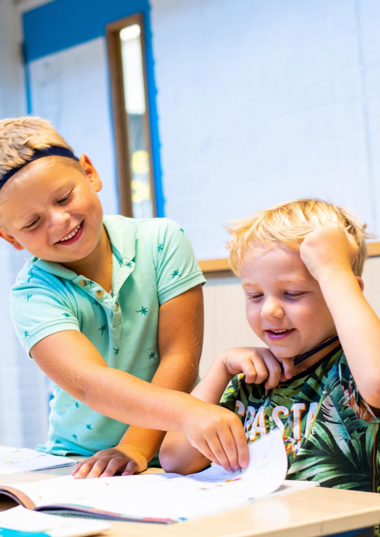 Twee kinderen die samenwerken aan een boek in CBS De Adelaar in Wolvega. Twee kinderen die samenwerken aan een boek in CBS De Adelaar in Wolvega.