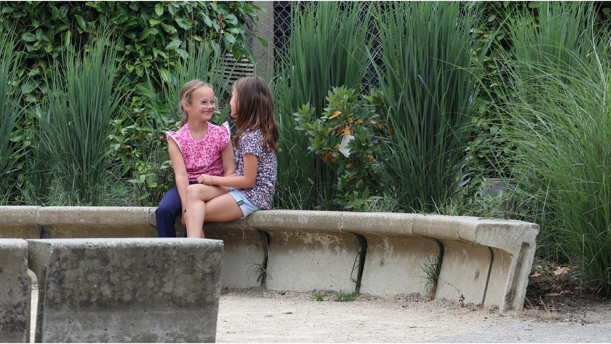 Twee kinderen lachen en praten op een bank op het schoolplein van Alberoschool Kindcentrum De Welle in Kruiningen. Twee kinderen lachen en praten op een bank op het schoolplein van Alberoschool Kindcentrum De Welle in Kruiningen.