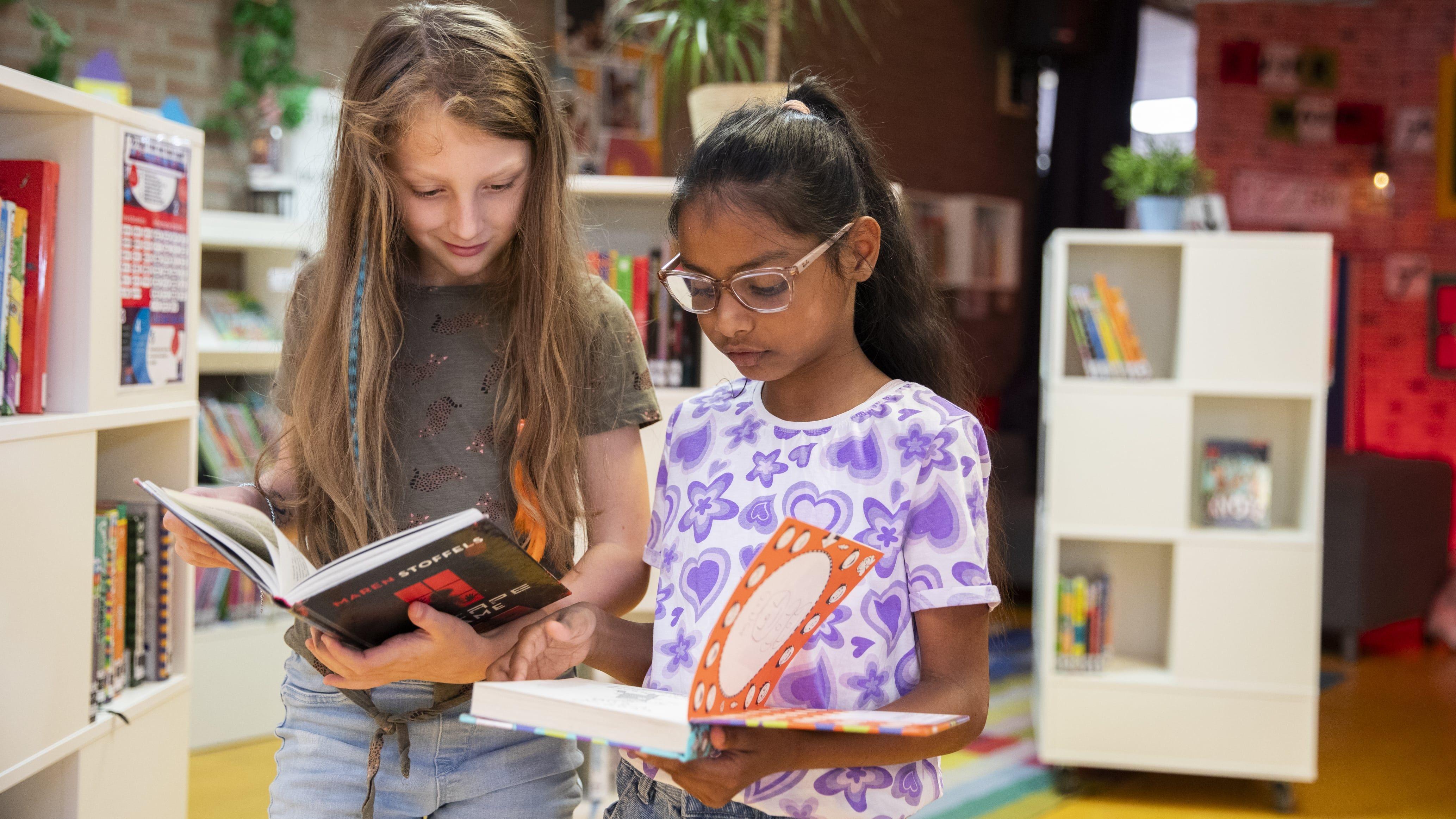Twee kinderen lezen boeken in de bibliotheek van O.b.s. De Vogelenzang in Spijkenisse. Twee kinderen lezen boeken in de bibliotheek van O.b.s. De Vogelenzang in Spijkenisse.