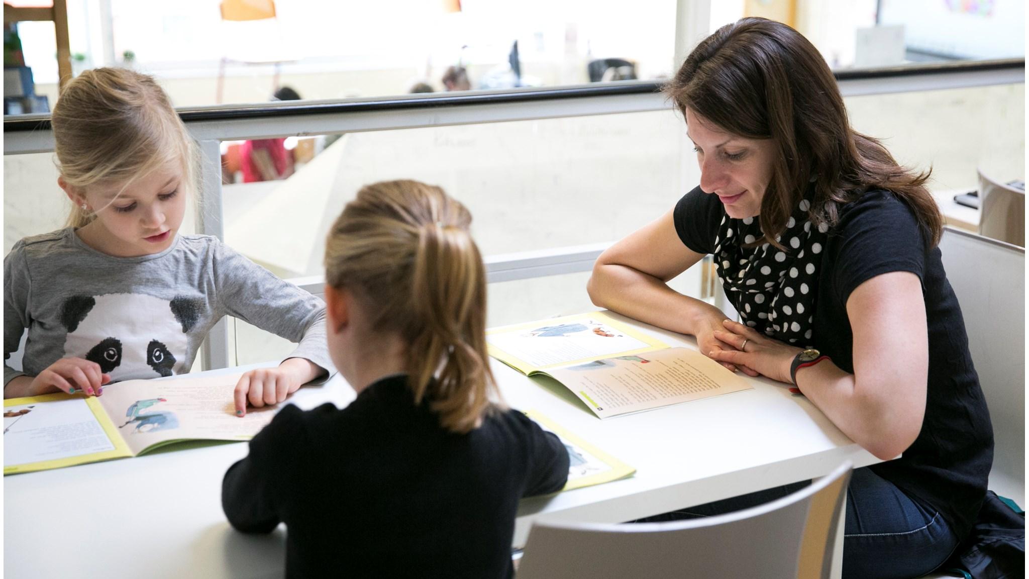 Twee kinderen lezen boeken met een lerares in de P.C. Jenaplanschool Zonnewereld in Vleuten. Twee kinderen lezen boeken met een lerares in de P.C. Jenaplanschool Zonnewereld in Vleuten.