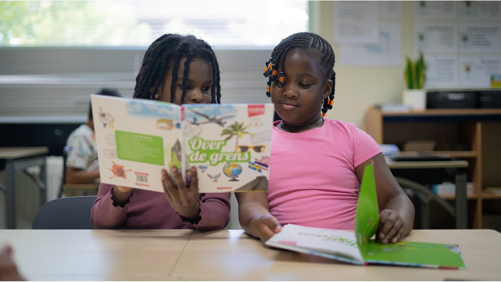 Twee kinderen lezen samen boeken in een klaslokaal van De Kleine Wereld in Almere. Twee kinderen lezen samen boeken in een klaslokaal van De Kleine Wereld in Almere.