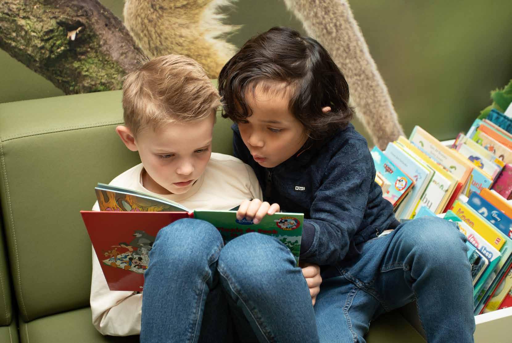Twee kinderen lezen samen een boek op een bank in basisschool Het Avontuur in Hoef en Haag.