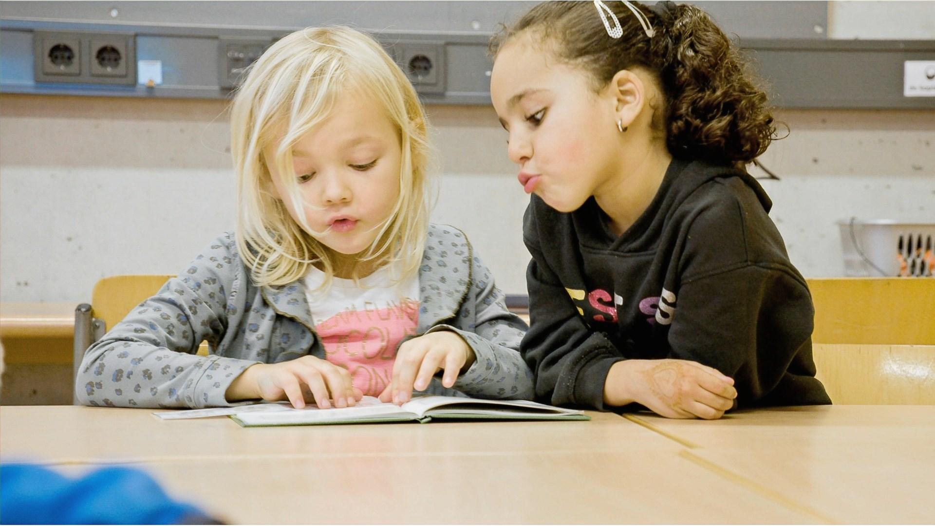 Twee kinderen lezen samen in de klas van school 'Joop en Willy Westerweel' in Amsterdam. Twee kinderen lezen samen in de klas van school 'Joop en Willy Westerweel' in Amsterdam.