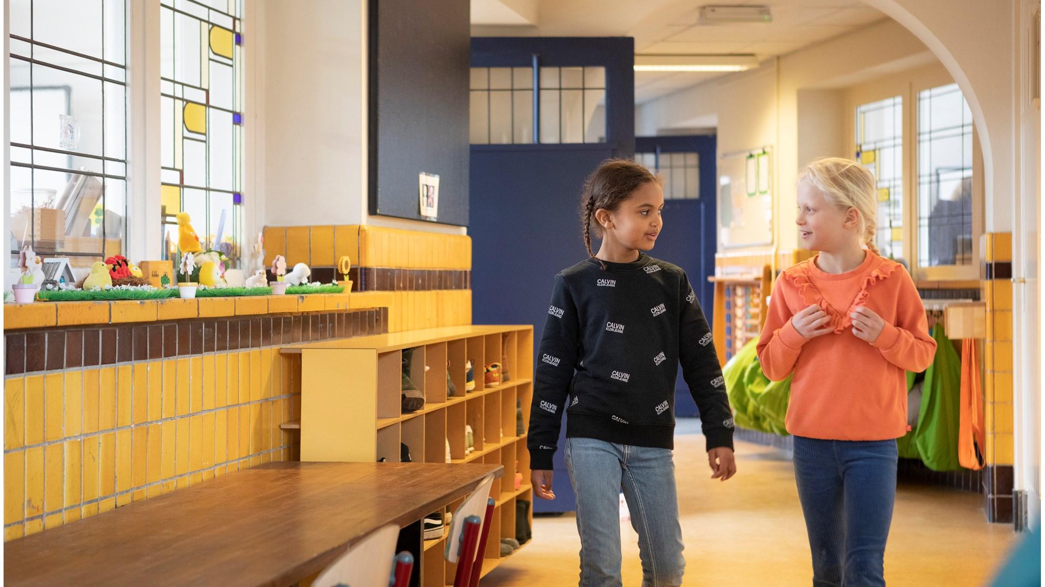 Twee kinderen lopen samen door het kleurrijke interieur van de Jacob Maris school in Rotterdam. Twee kinderen lopen samen door het kleurrijke interieur van de Jacob Maris school in Rotterdam.