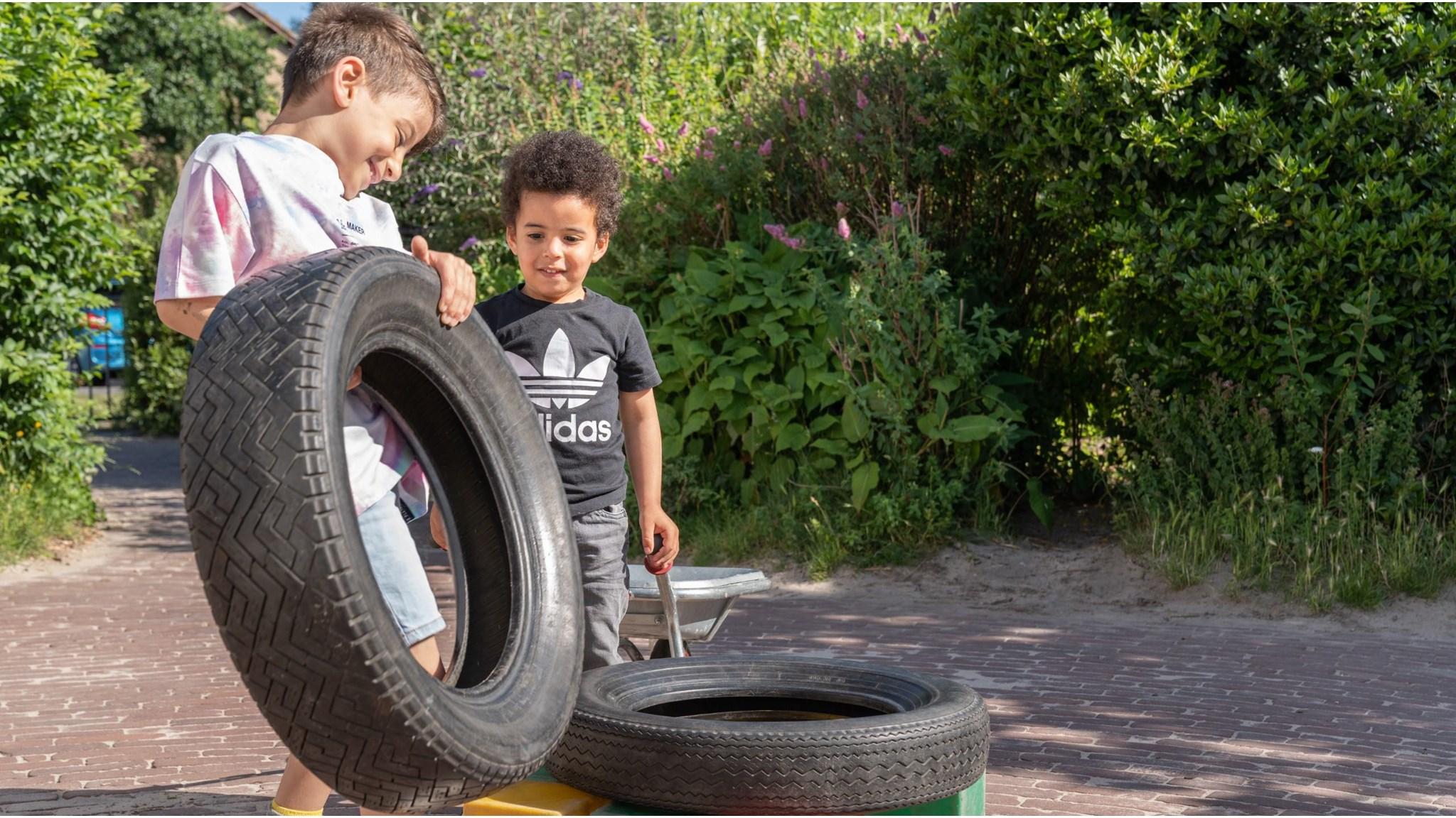 Twee kinderen spelen met autobanden op het schoolplein van Openbare Basisschool de Sterrenkijker in Beverwijk. Twee kinderen spelen met autobanden op het schoolplein van Openbare Basisschool de Sterrenkijker in Beverwijk.