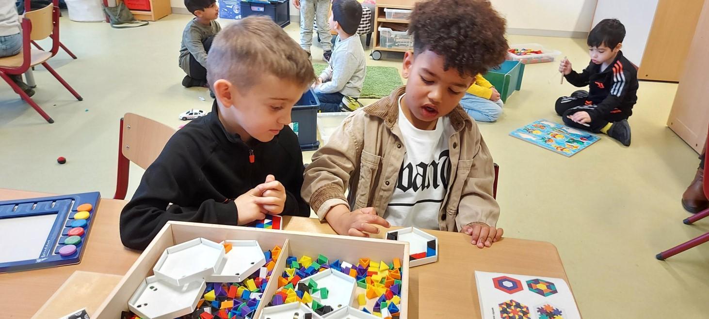 Twee kinderen spelen met kleurrijke bouwstukken in het klaslokaal van de Jan Ligthartschool in Den Haag. Twee kinderen spelen met kleurrijke bouwstukken in het klaslokaal van de Jan Ligthartschool in Den Haag.