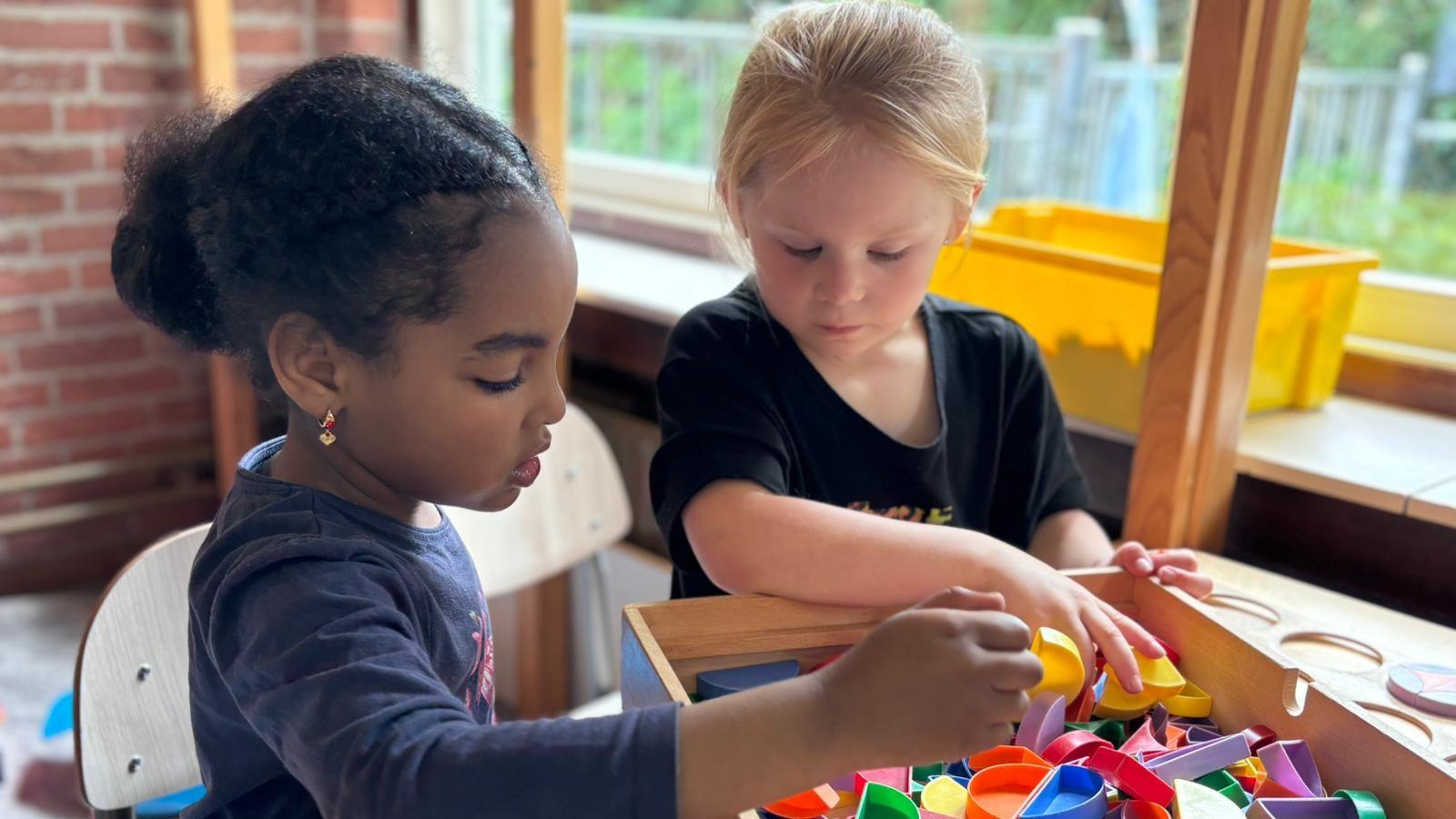 Twee kinderen spelen met kleurrijke speelgoedvormen in KC De Ruimte in Kudelstaart. Twee kinderen spelen met kleurrijke speelgoedvormen in KC De Ruimte in Kudelstaart.