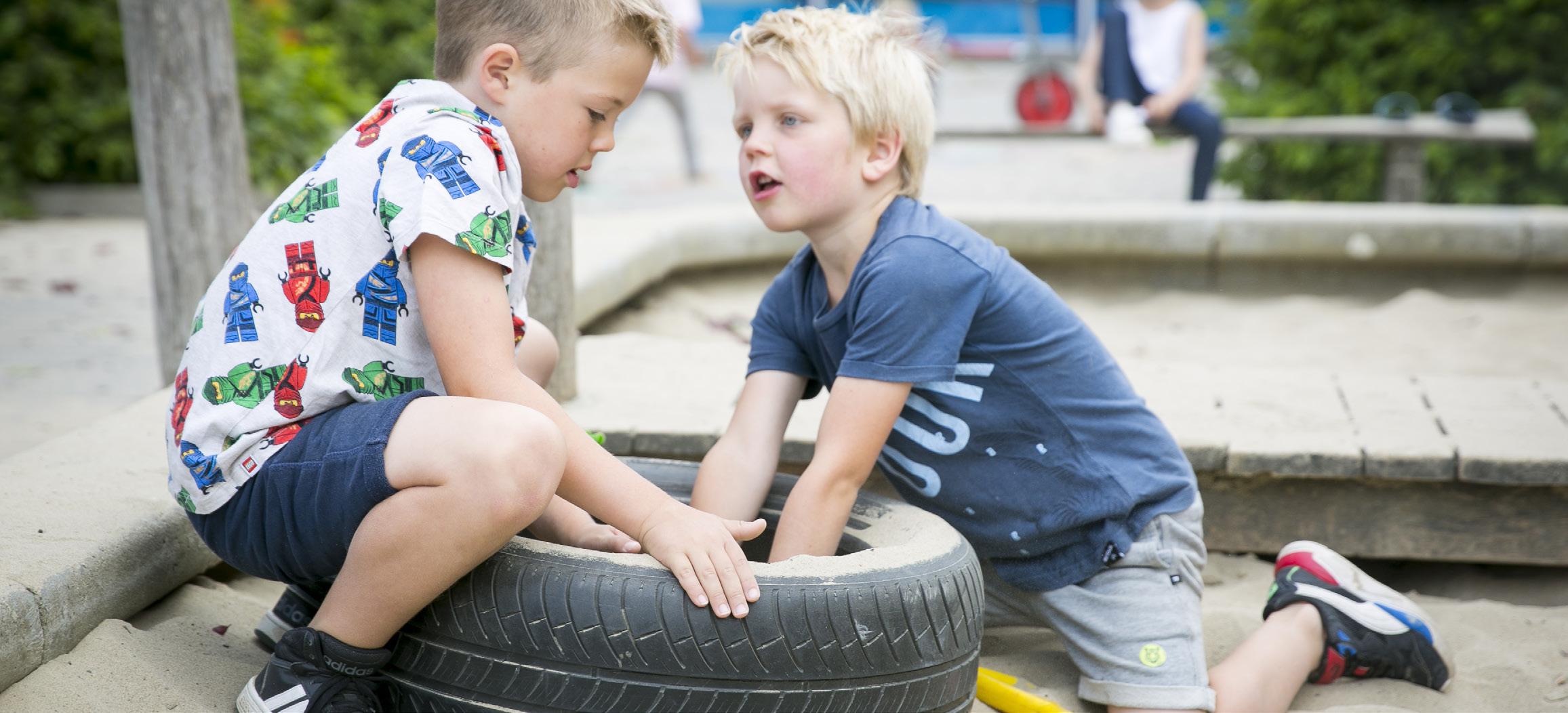 Twee kinderen spelen samen met een autoband op het schoolplein van De Fontein Houten. Twee kinderen spelen samen met een autoband op het schoolplein van De Fontein Houten.