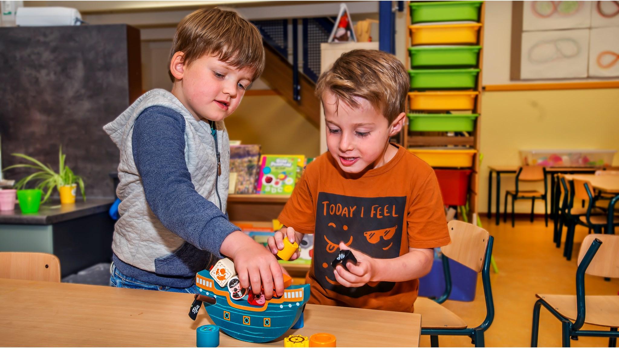Twee kinderen spelen samen met een houten speelgoedboot in klaslokaal van Kbs St. Joseph in Breda. Twee kinderen spelen samen met een houten speelgoedboot in klaslokaal van Kbs St. Joseph in Breda.