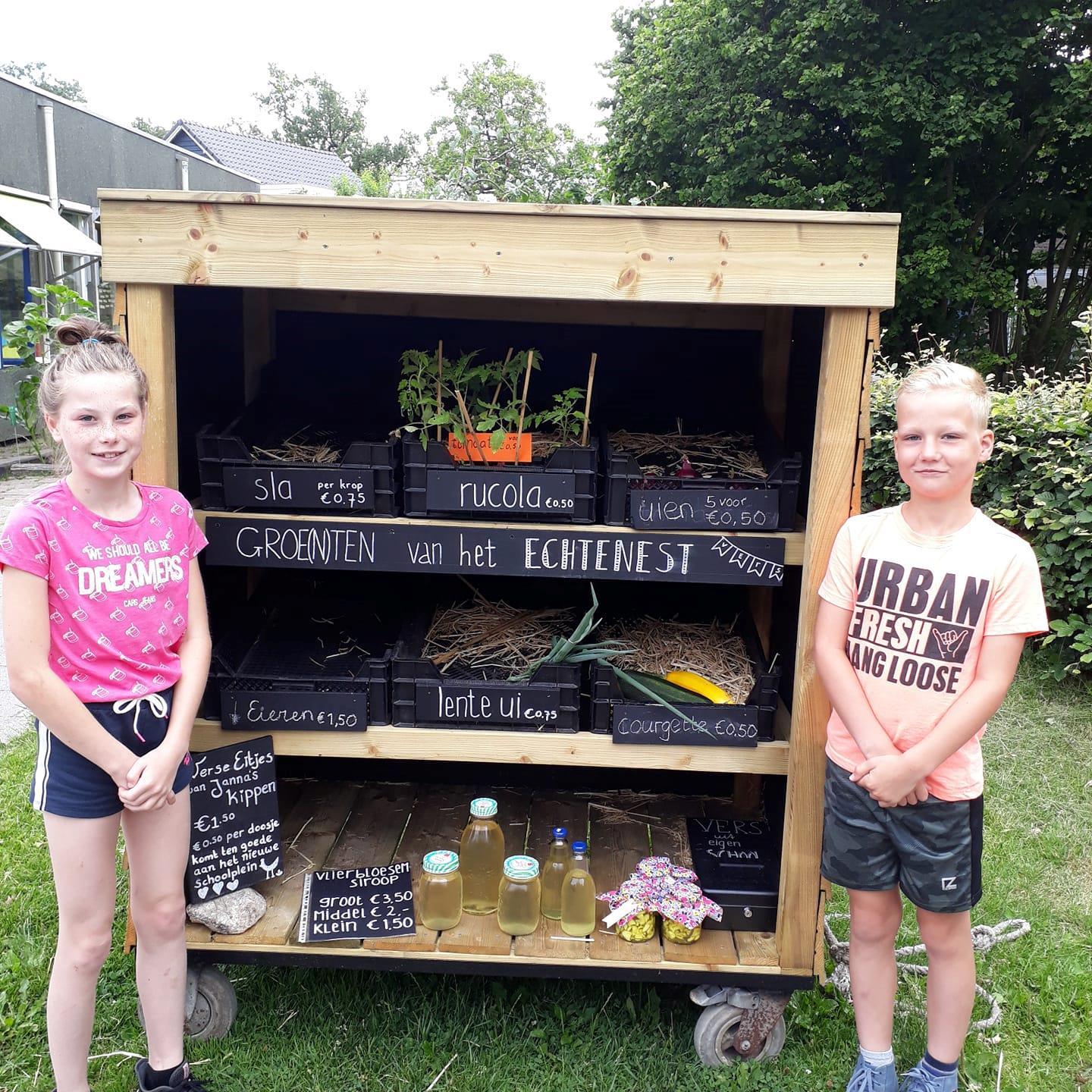 Twee kinderen staan naast een groentenkraam van KC 't Echtenest in Echten (Drenthe). Twee kinderen staan naast een groentenkraam van KC 't Echtenest in Echten (Drenthe).