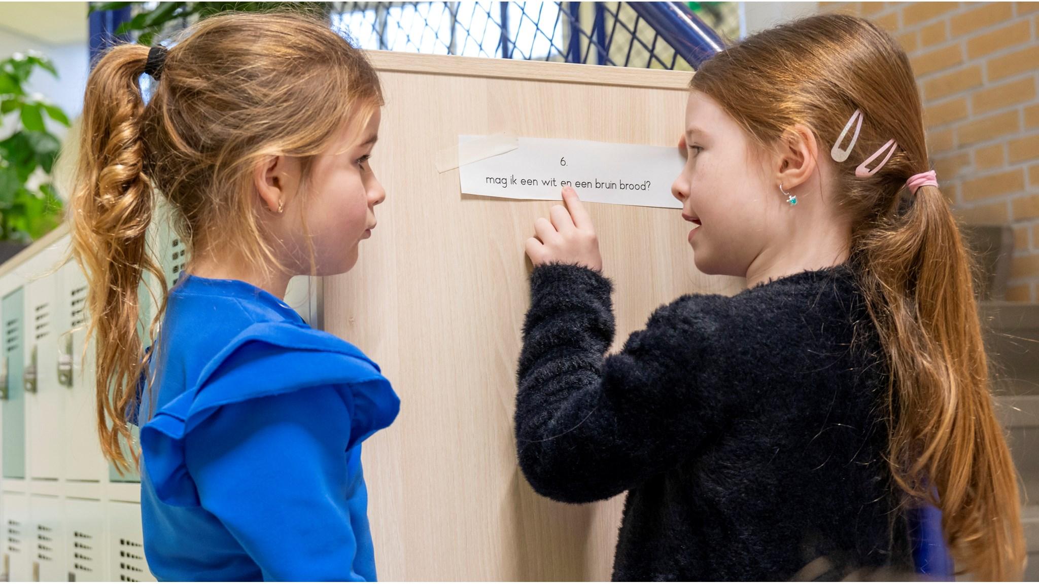 Twee kinderen van Basisschool Hoffenne in Noordwijk (Zuid-Holland) lezen samen een tekst op een muur. Twee kinderen van Basisschool Hoffenne in Noordwijk (Zuid-Holland) lezen samen een tekst op een muur.